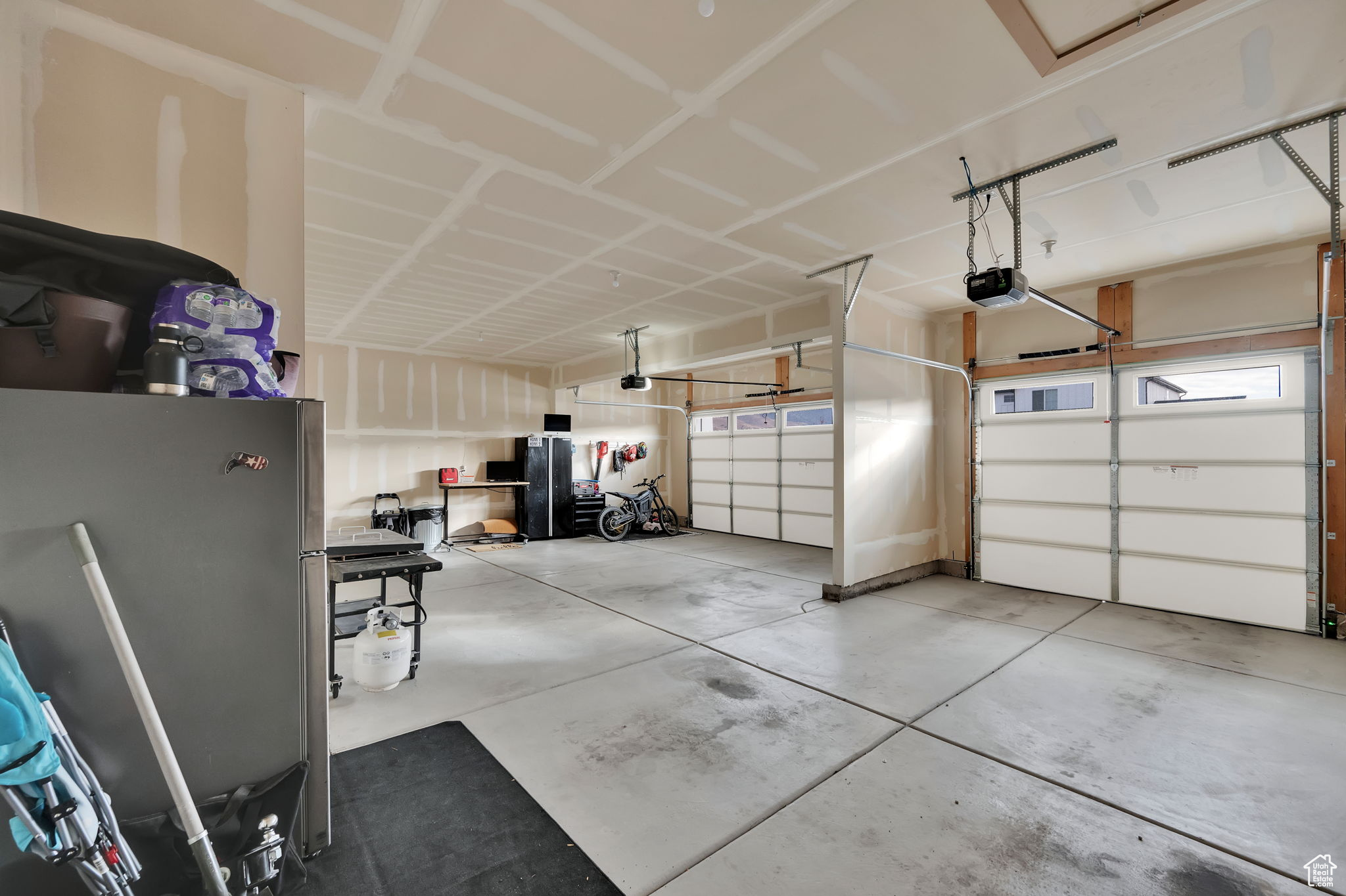 Garage with stainless steel fridge and a garage door opener