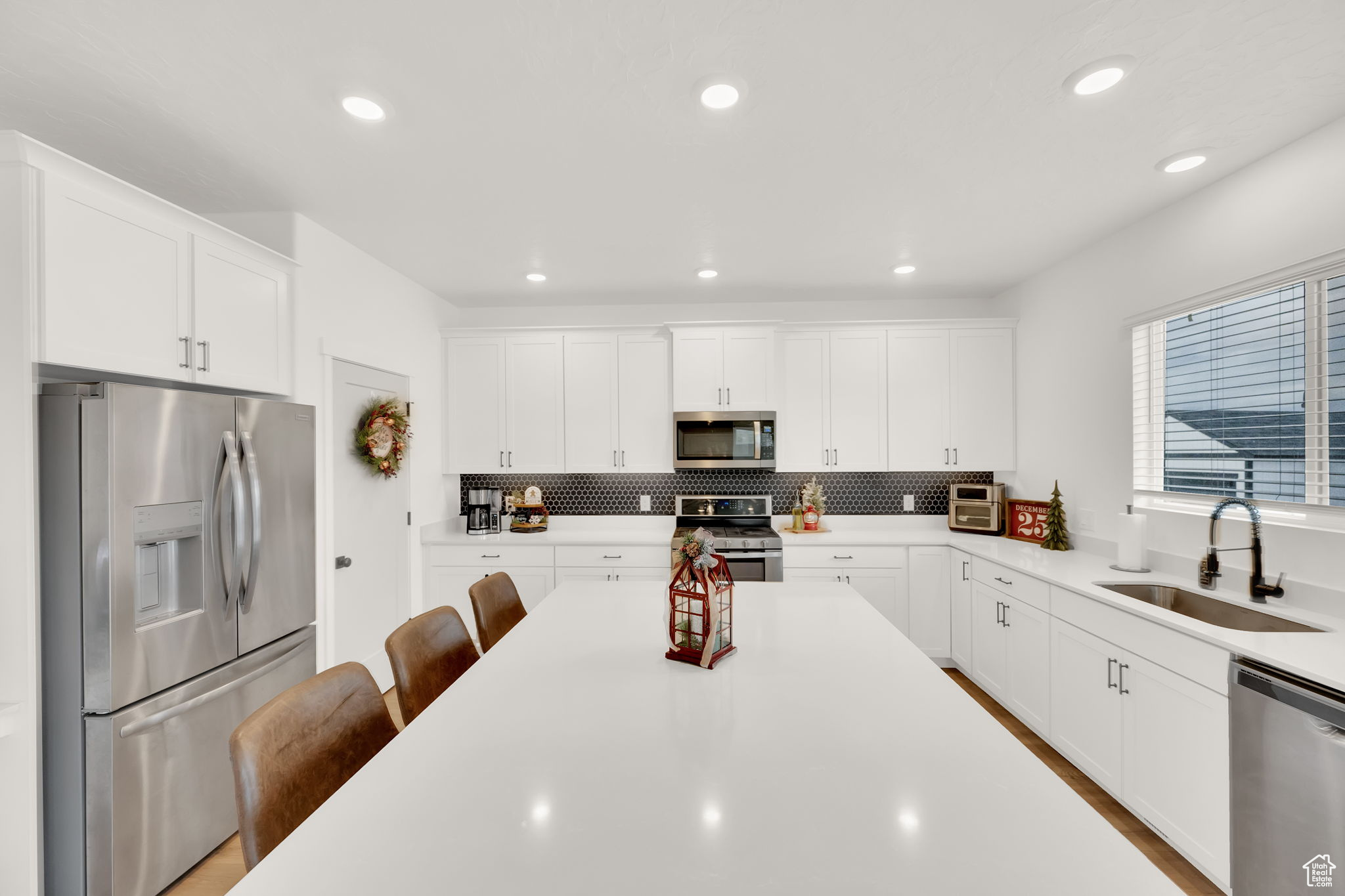 Kitchen featuring white cabinets, backsplash, sink, and appliances with stainless steel finishes