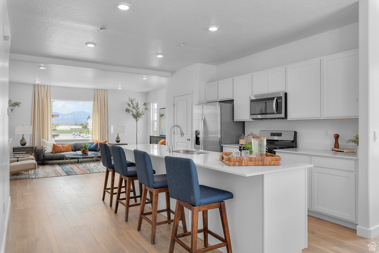 Kitchen featuring a center island with sink, sink, a breakfast bar area, white cabinetry, and stainless steel appliances