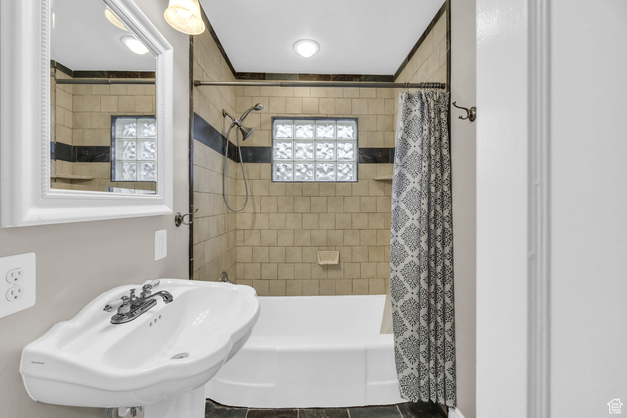 Bathroom featuring tile patterned flooring, shower / tub combo with curtain, and sink