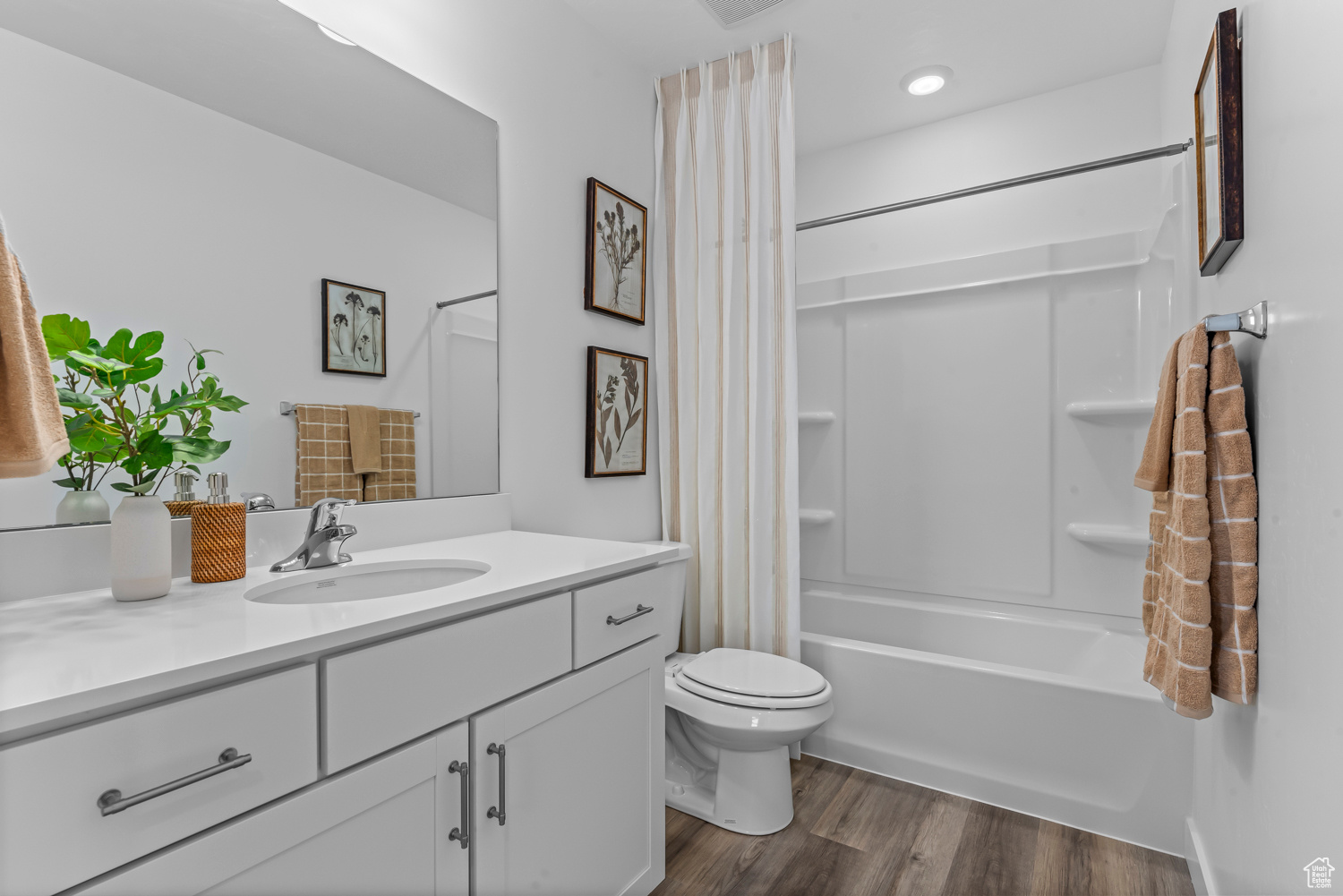 Full bathroom with vanity, hardwood / wood-style flooring, toilet, and shower / bath combo with shower curtain