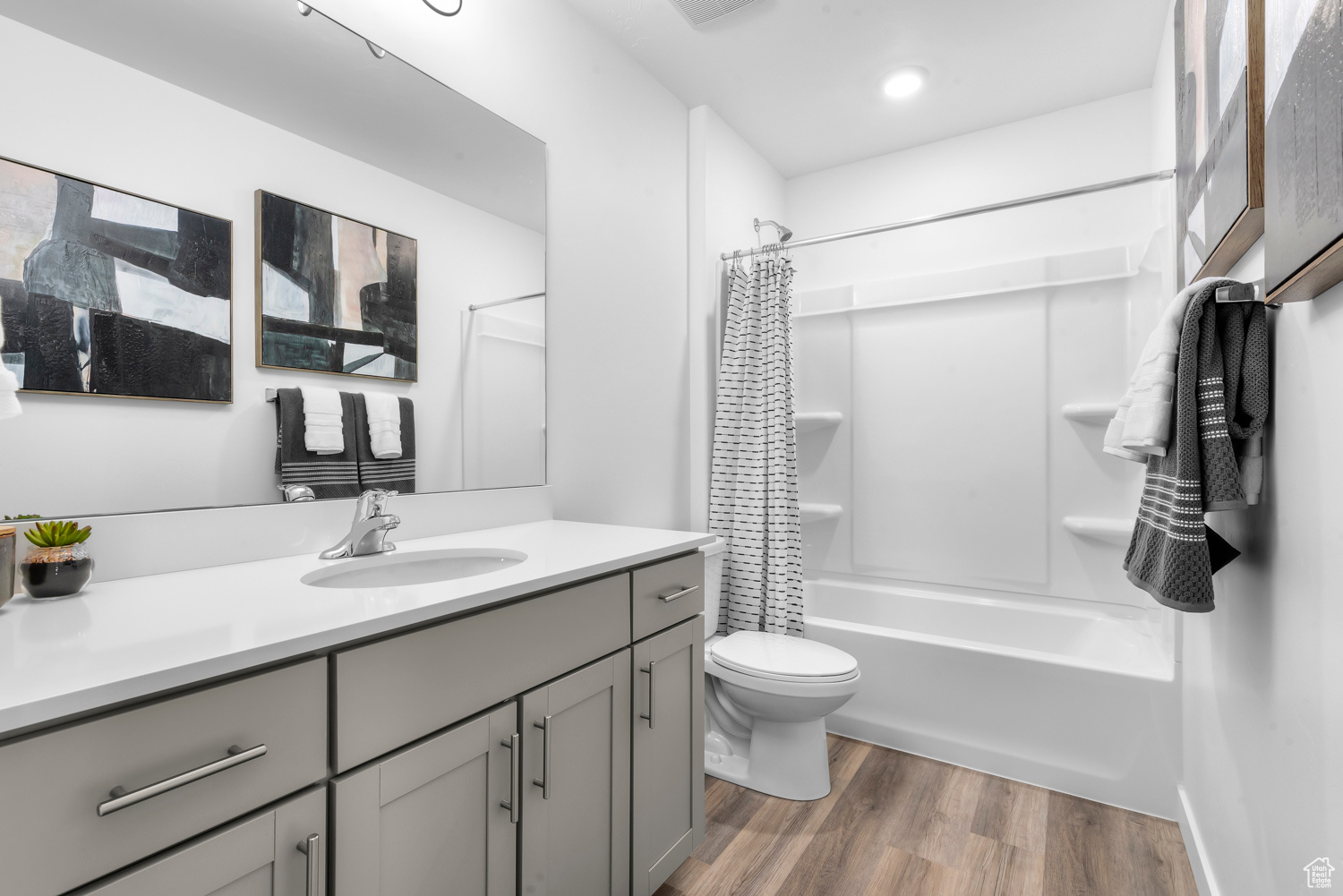 Full bathroom with shower / bath combo with shower curtain, vanity, wood-type flooring, and toilet