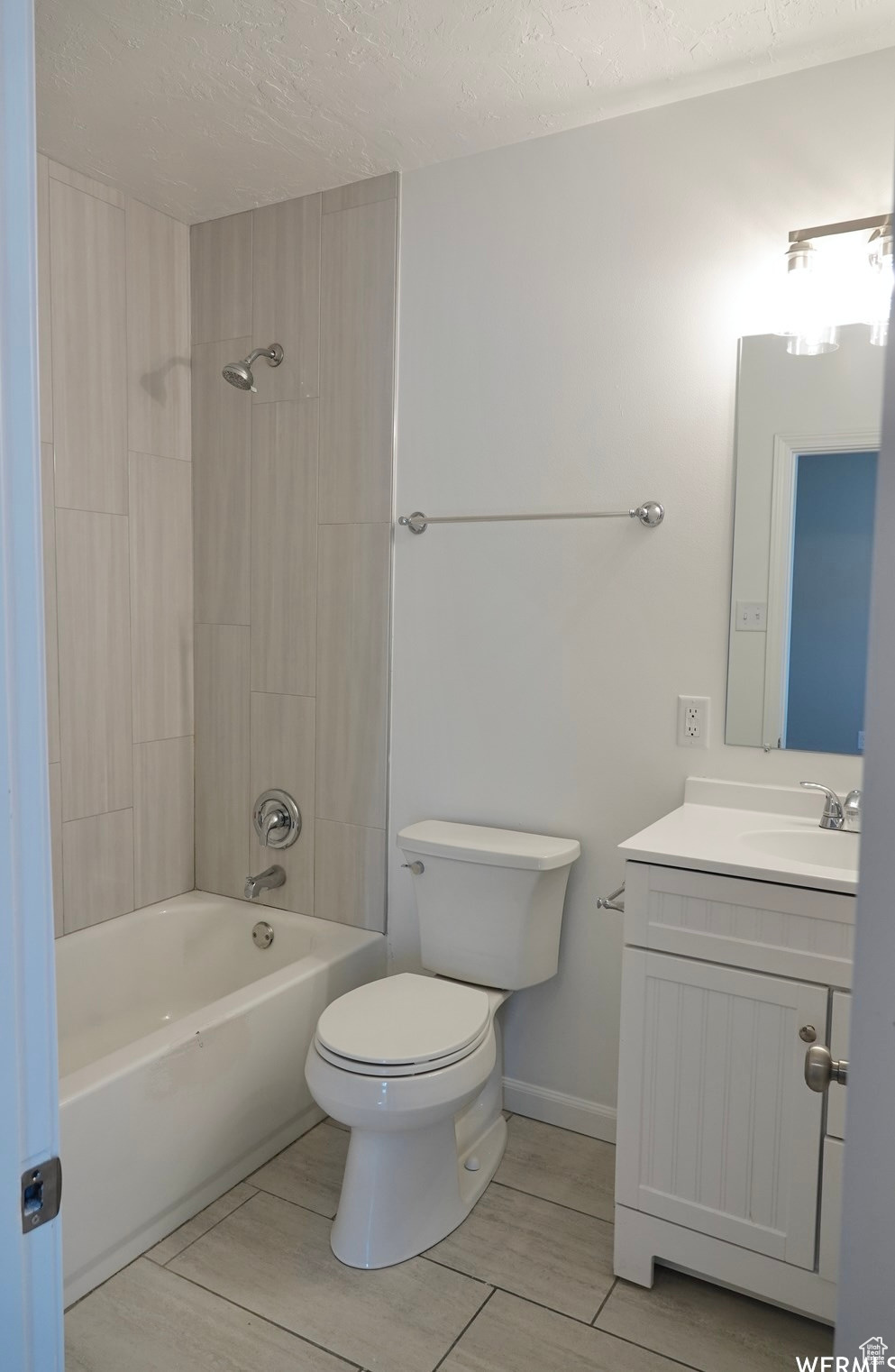 Full bathroom with vanity, a textured ceiling, toilet, and tiled shower / bath