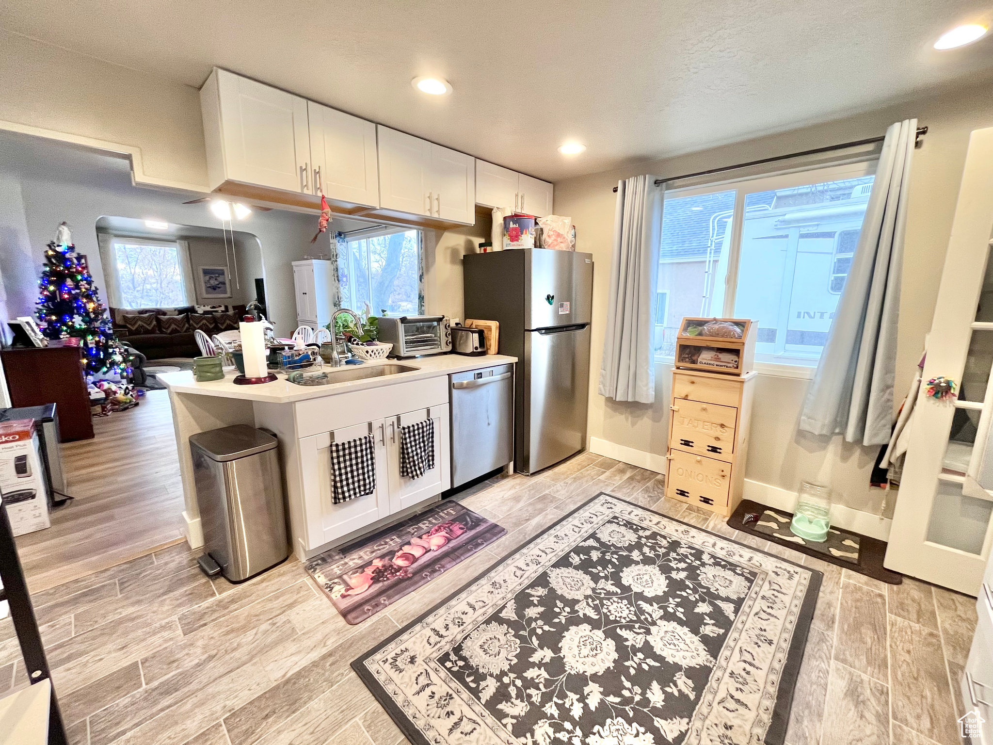 Kitchen featuring kitchen peninsula, white cabinetry, sink, and appliances with stainless steel finishes