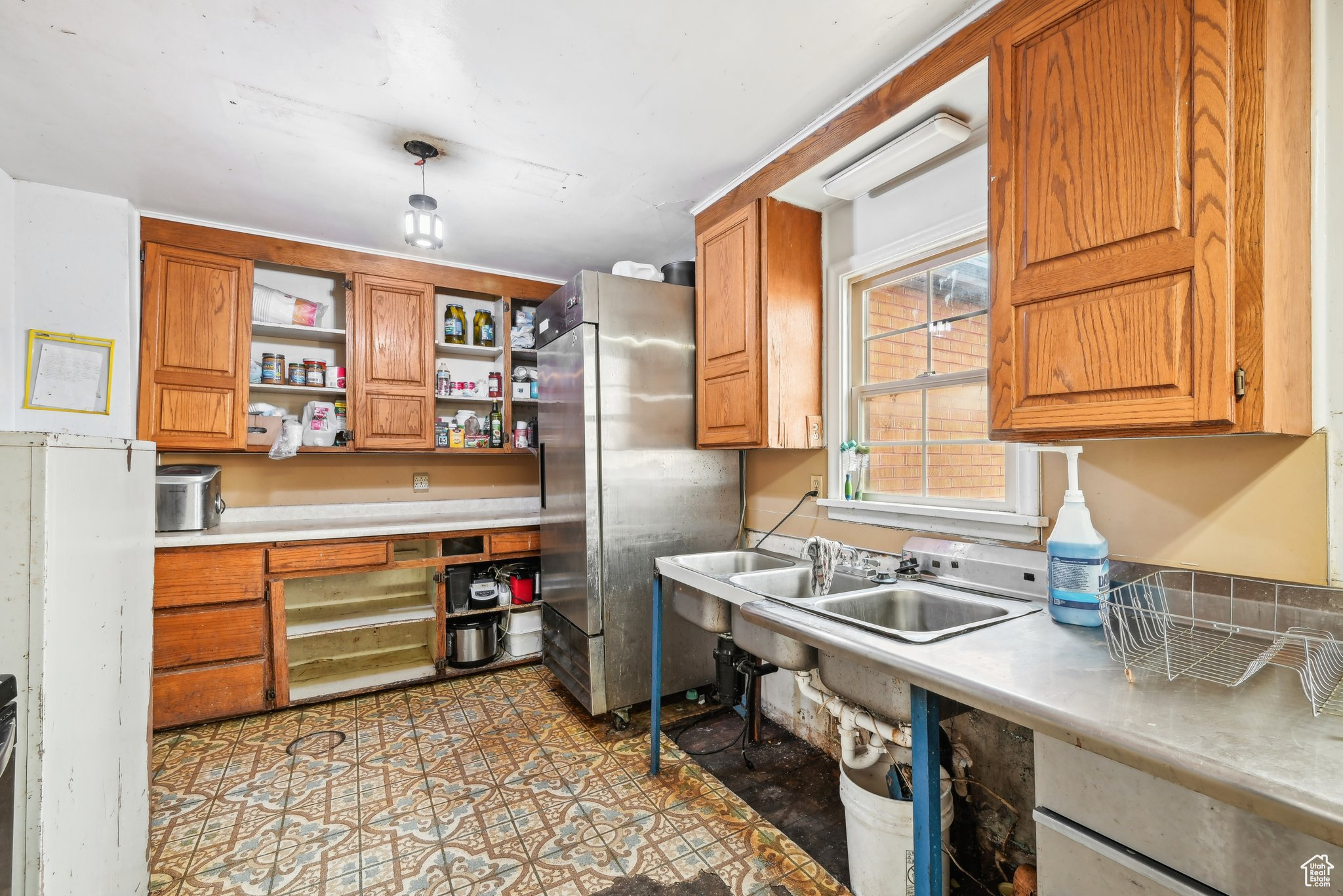 Kitchen with stainless steel fridge, light tile patterned floors, and sink