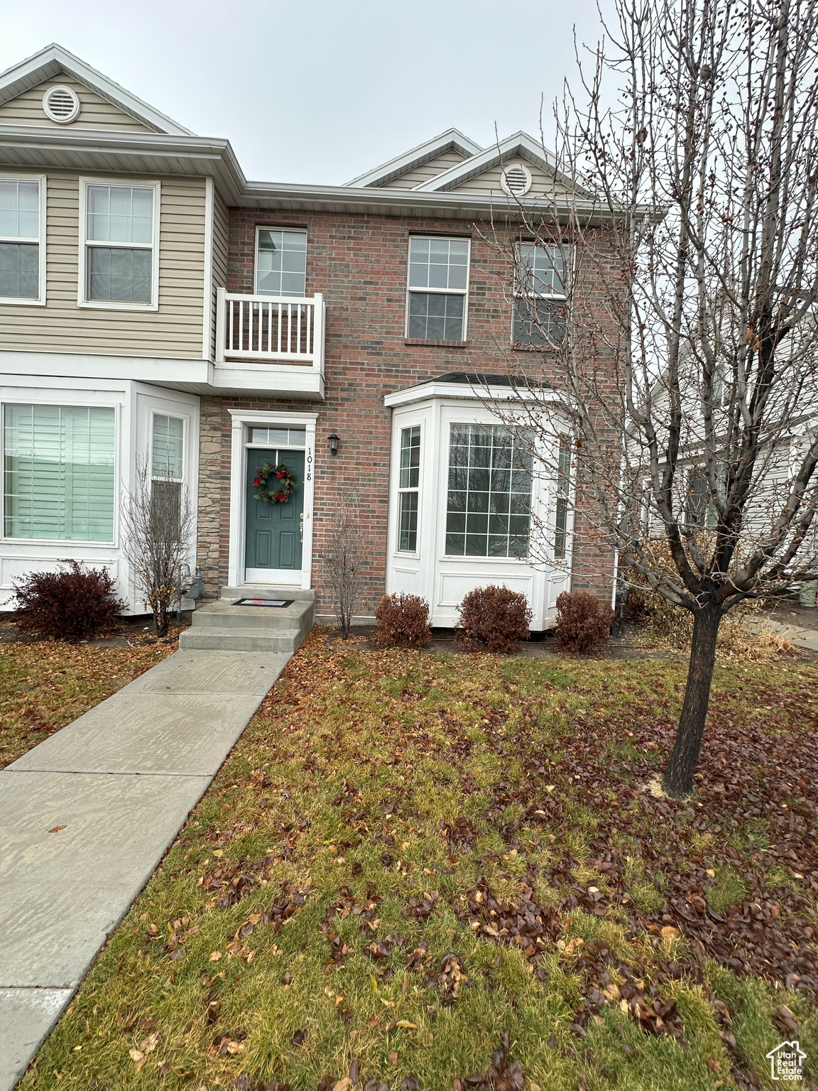 View of front of house featuring a balcony and a front yard