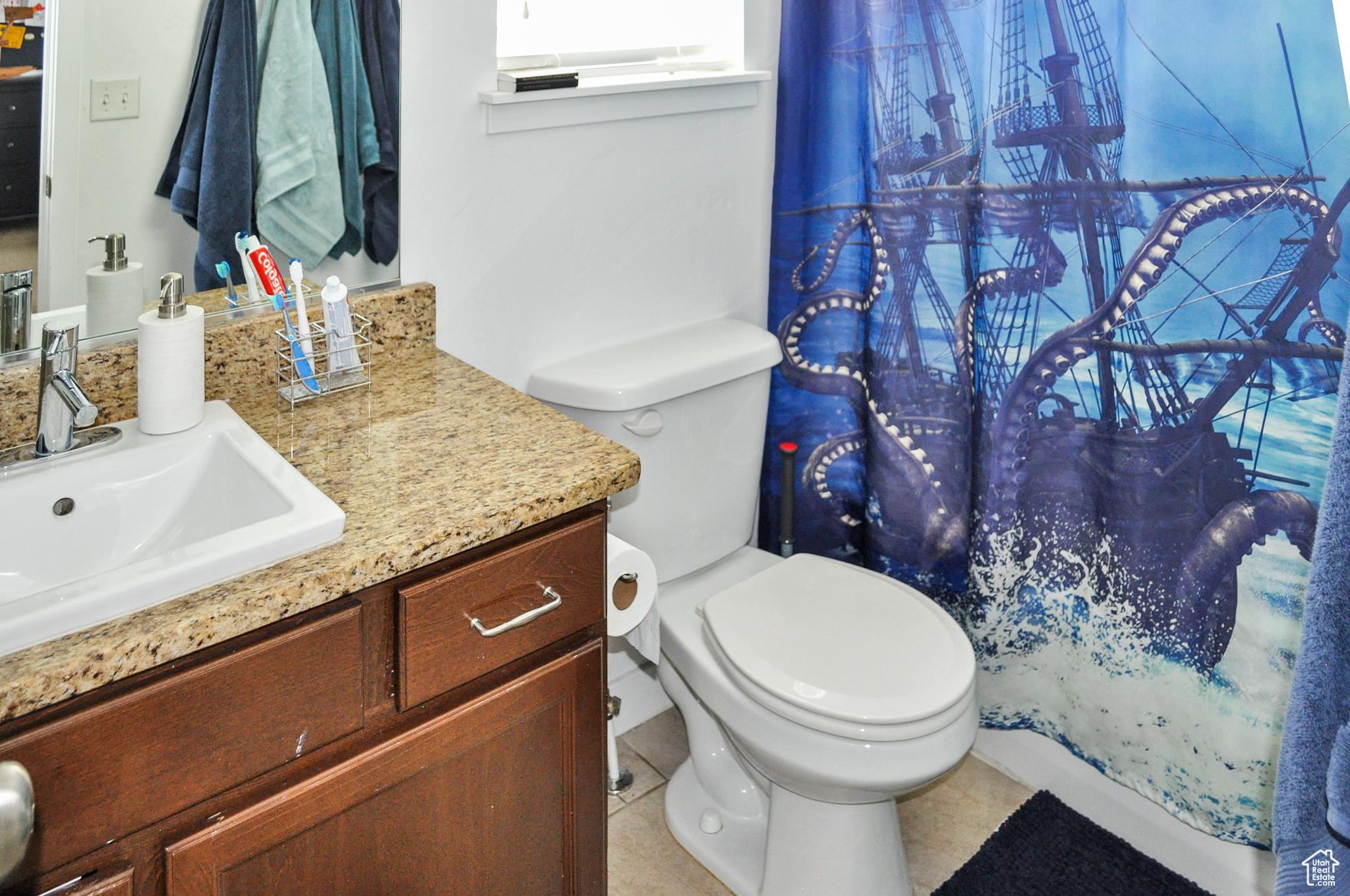 Bathroom featuring tile patterned flooring, vanity, toilet, and curtained shower