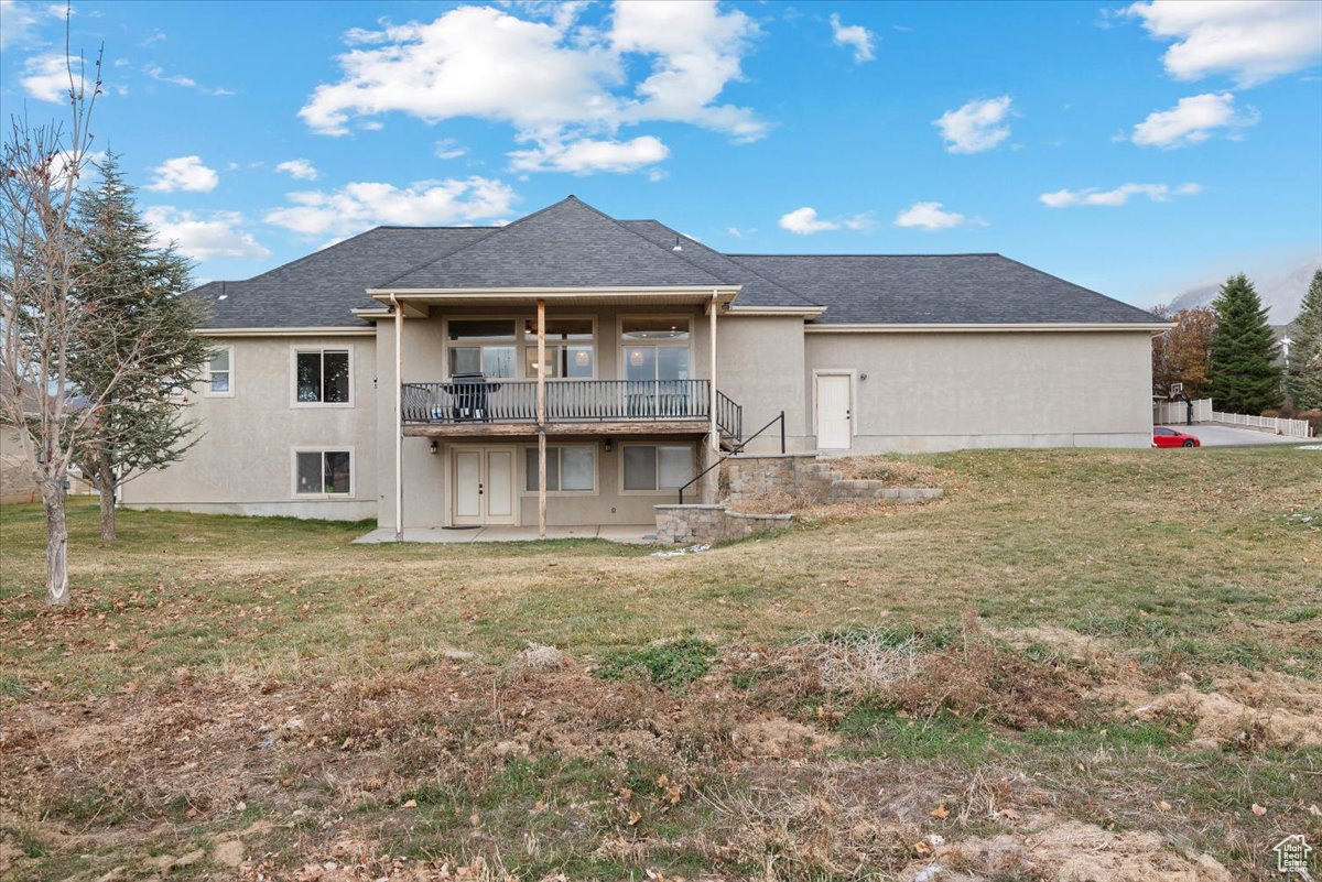 Back of house with a lawn and a patio