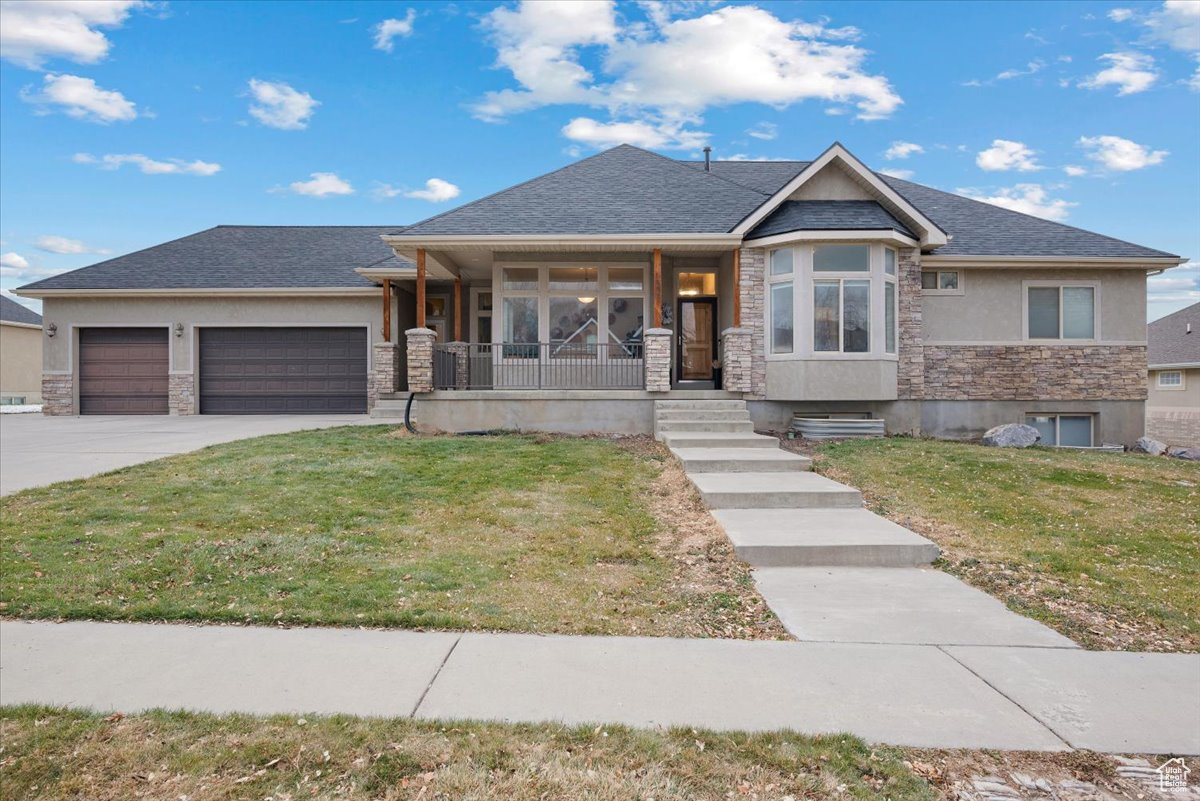 View of front of home with a front yard, a porch, and a garage