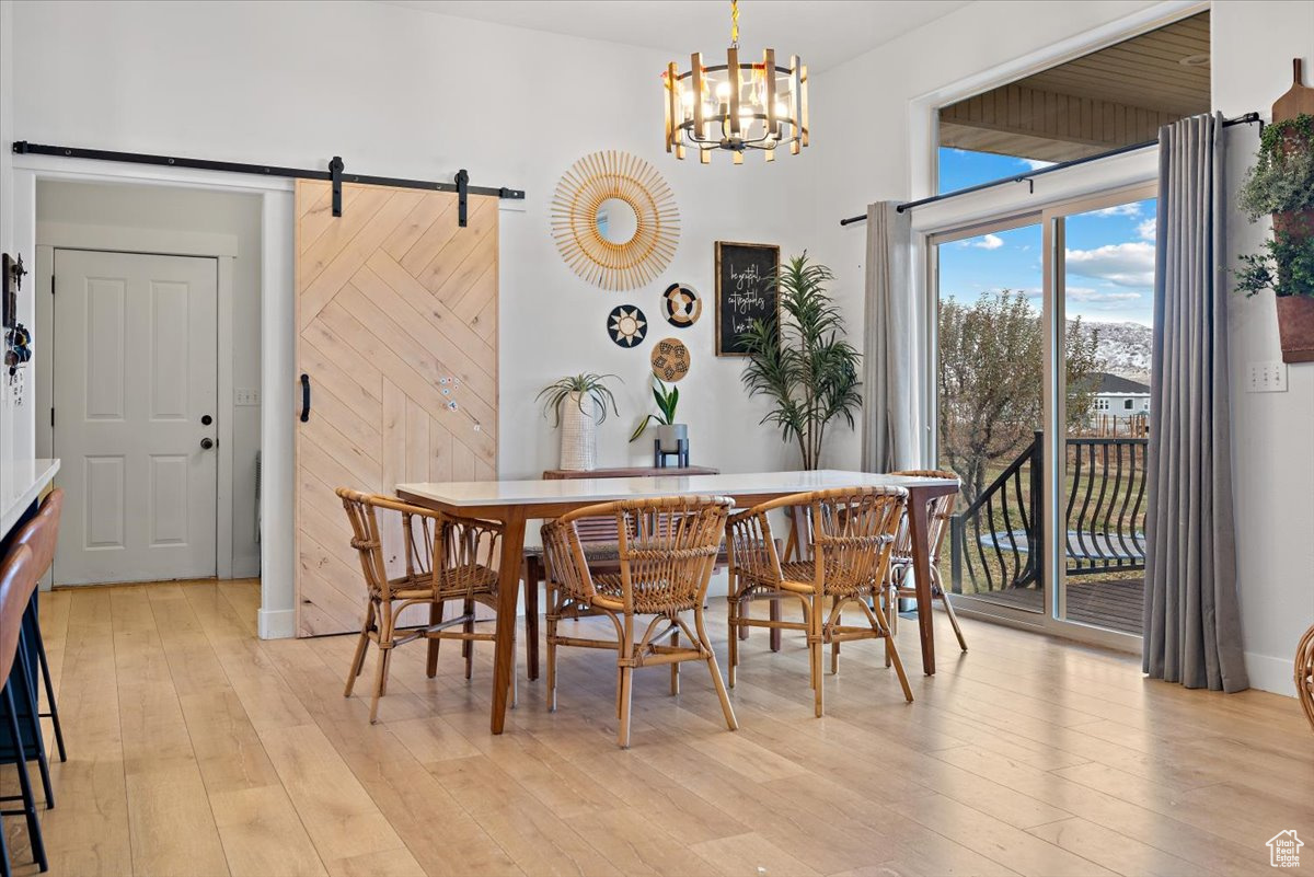 Dining space featuring a notable chandelier, a barn door, and light hardwood / wood-style flooring