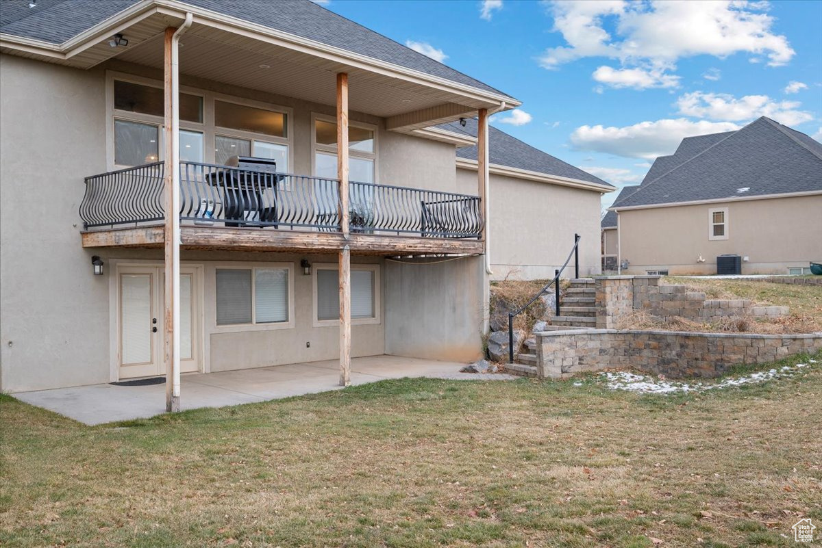 Back of house featuring a yard, cooling unit, and a patio area