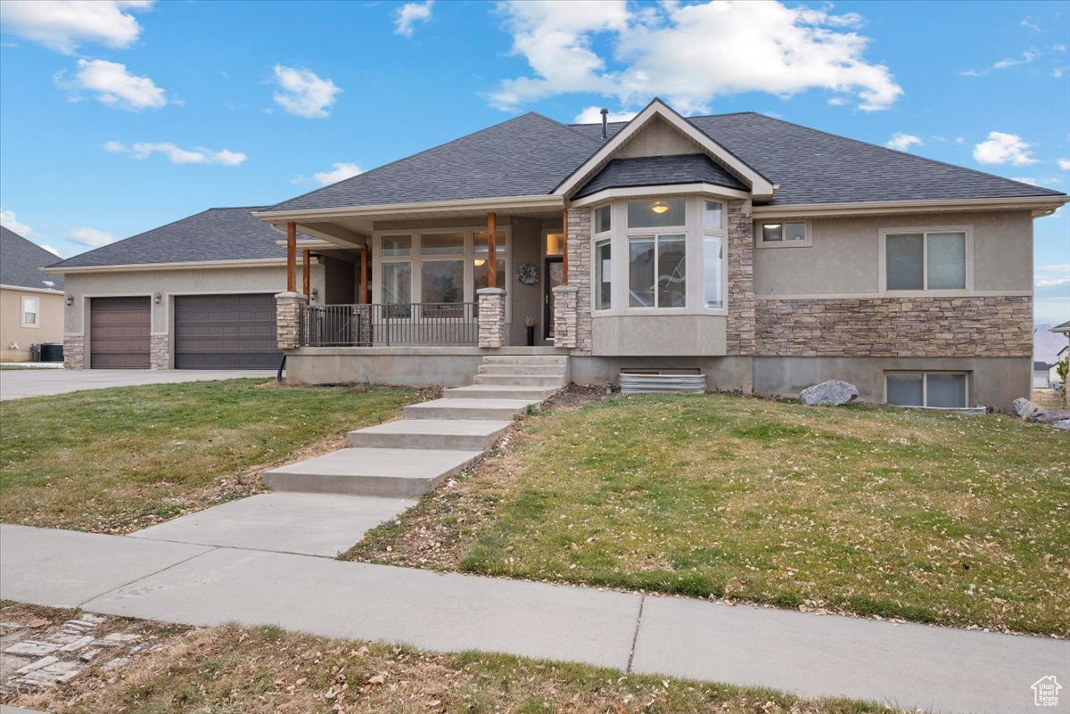 View of front of home featuring a front yard, a porch, and a garage