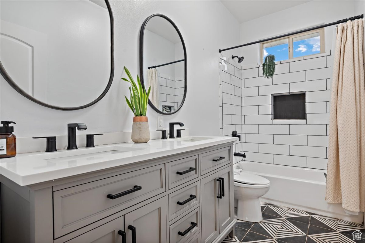 Full bathroom with tile patterned floors, vanity, shower / bath combo, and toilet