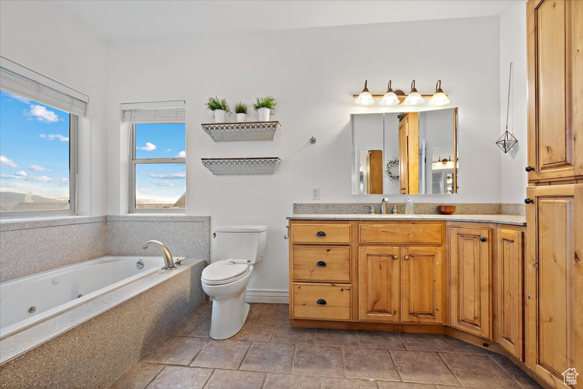 Bathroom featuring tiled tub, vanity, and toilet