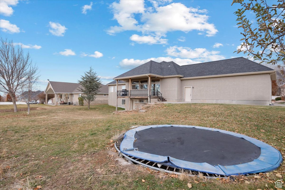 Rear view of property featuring a lawn and a trampoline