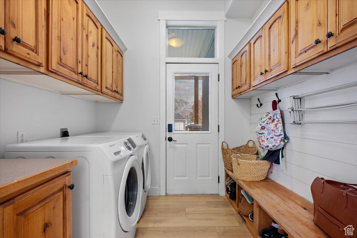 Washroom featuring light hardwood / wood-style floors, cabinets, and washing machine and dryer