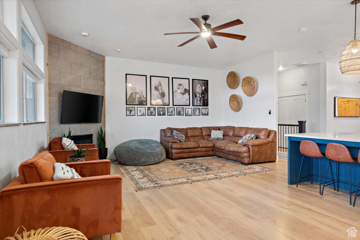 Living room with a tile fireplace, ceiling fan, and light hardwood / wood-style flooring