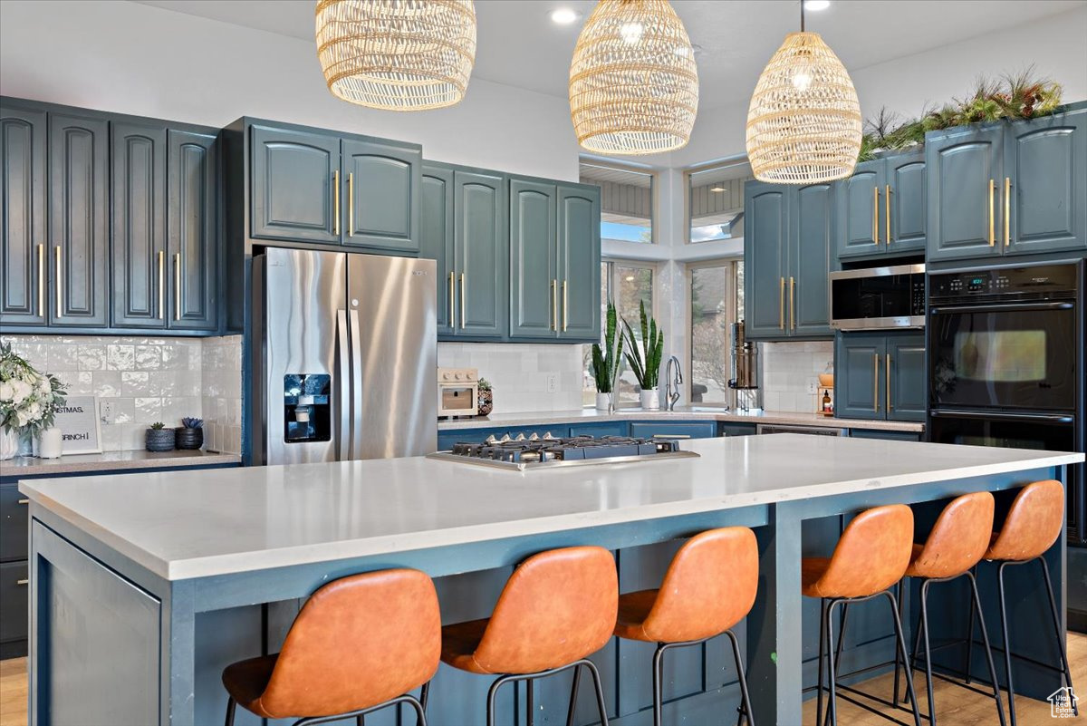 Kitchen with a center island, backsplash, appliances with stainless steel finishes, and a chandelier