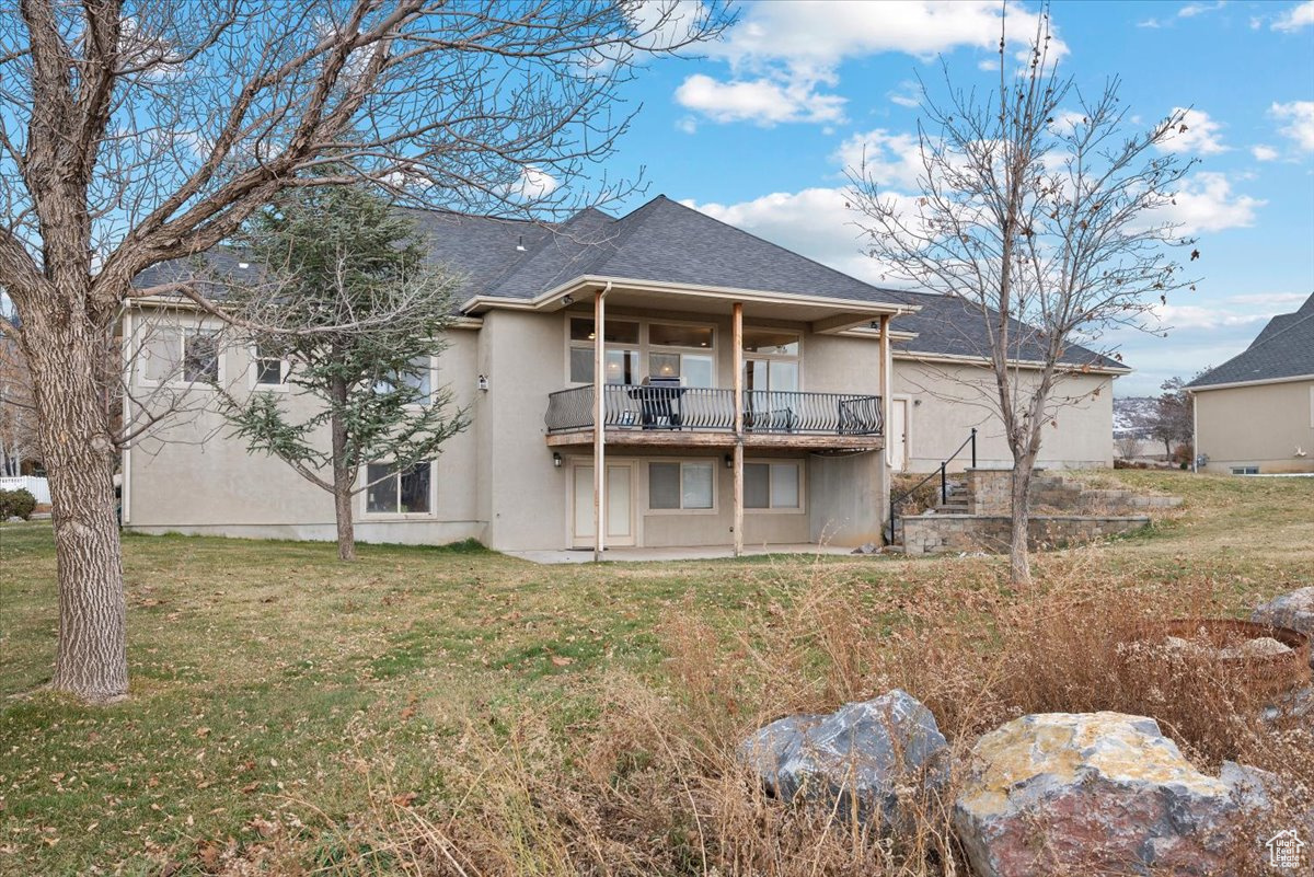 Rear view of house featuring a lawn and a balcony