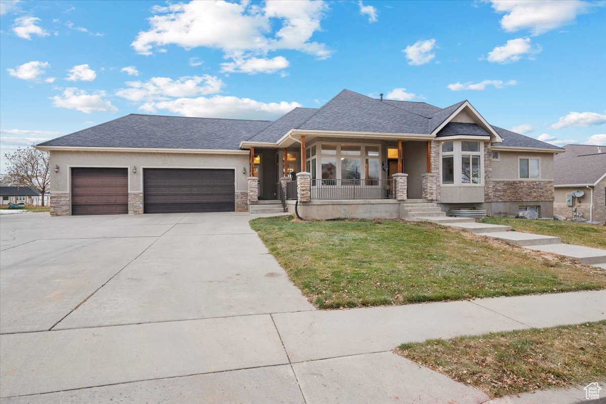 View of front of home featuring covered porch, a garage, and a front lawn