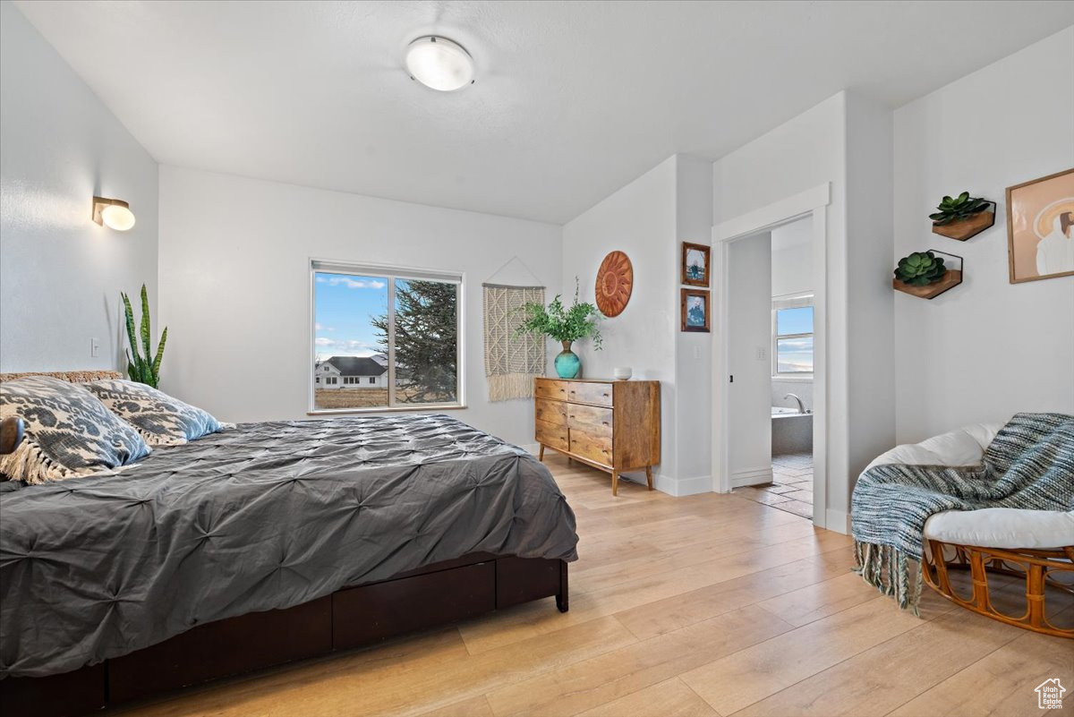 Bedroom with light hardwood / wood-style floors and ensuite bath