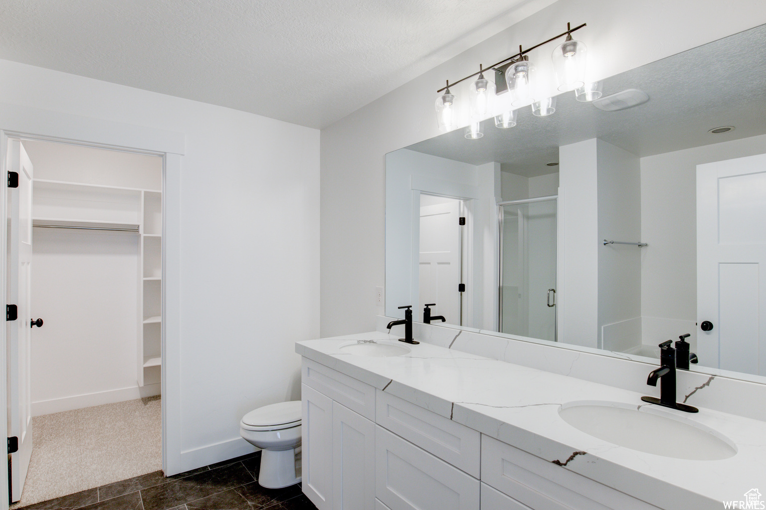 Bathroom with a shower with door, vanity, a textured ceiling, and toilet