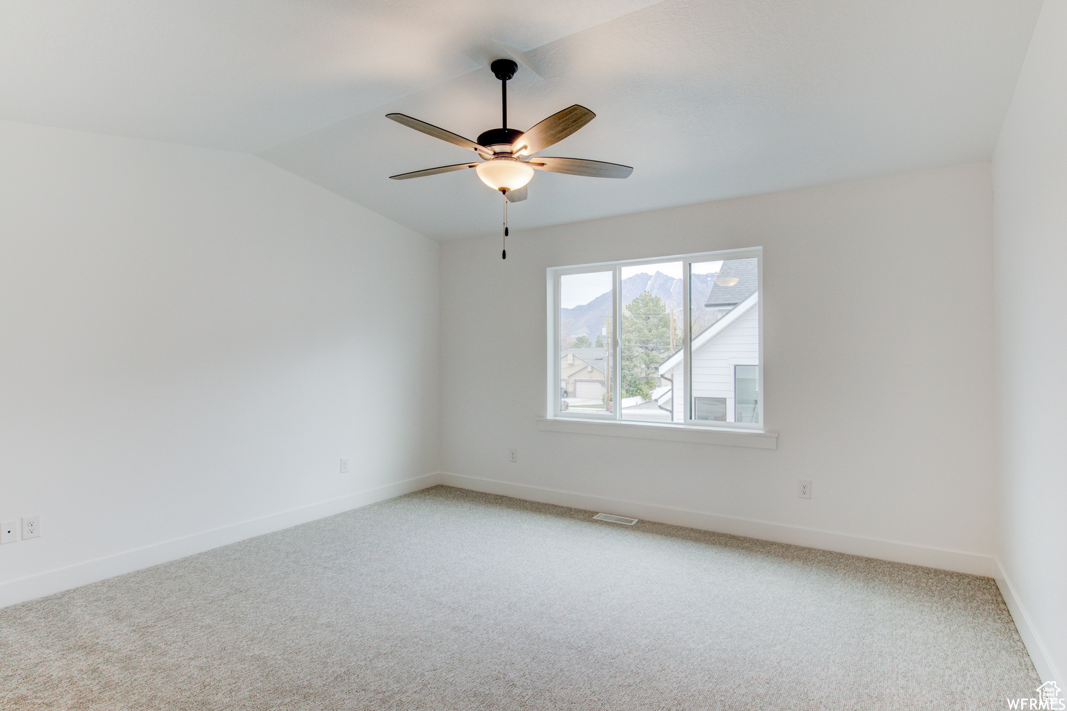 Carpeted spare room with ceiling fan and vaulted ceiling