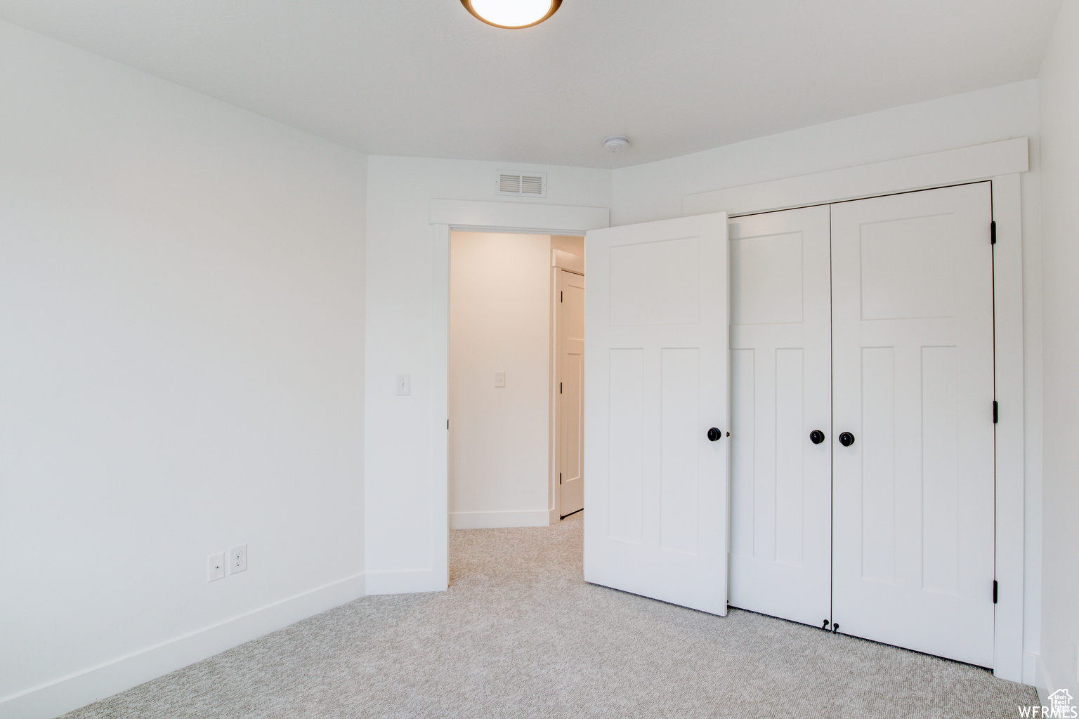 Unfurnished bedroom featuring light colored carpet and a closet