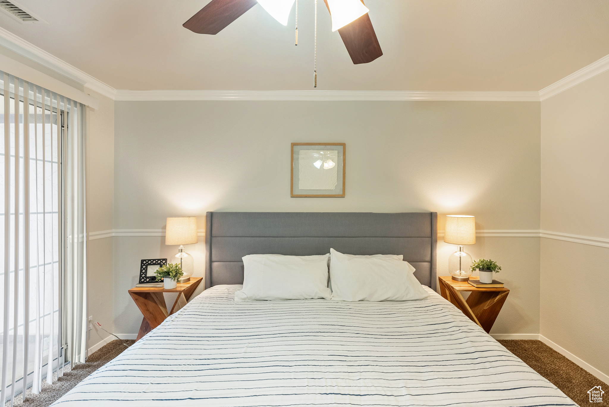 Carpeted bedroom featuring ceiling fan and ornamental molding