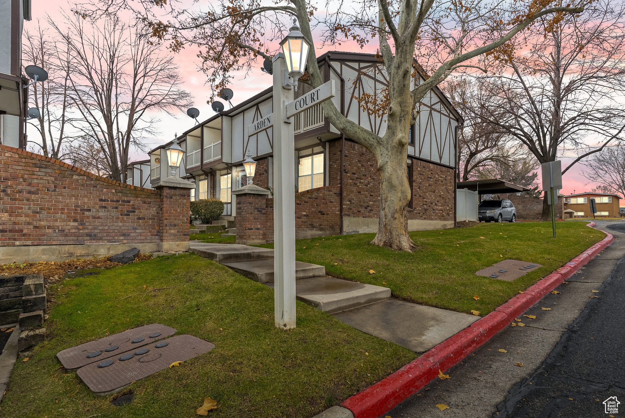 Property exterior at dusk with a balcony and a lawn