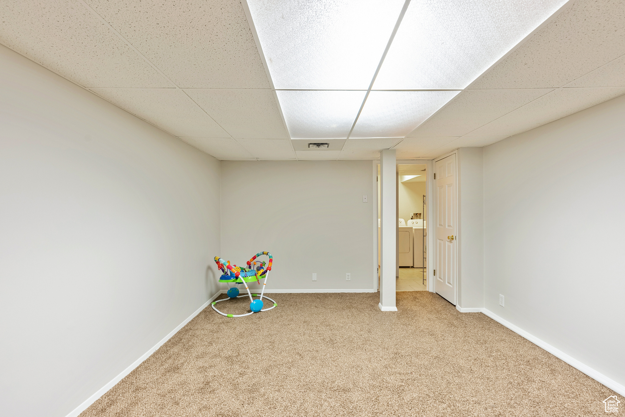 Game room with light carpet, washing machine and dryer, and a drop ceiling