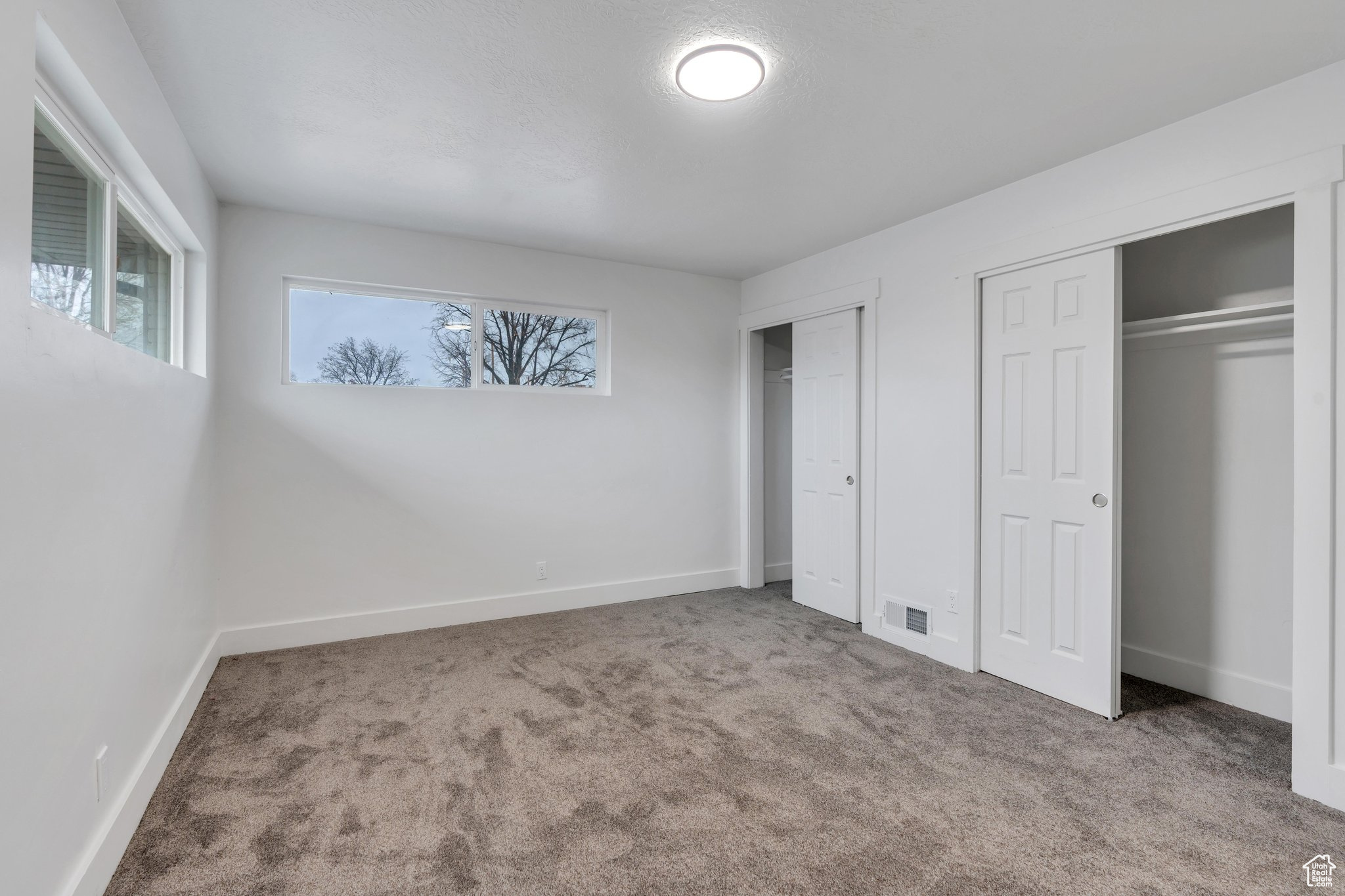 Unfurnished bedroom featuring carpet and two closets