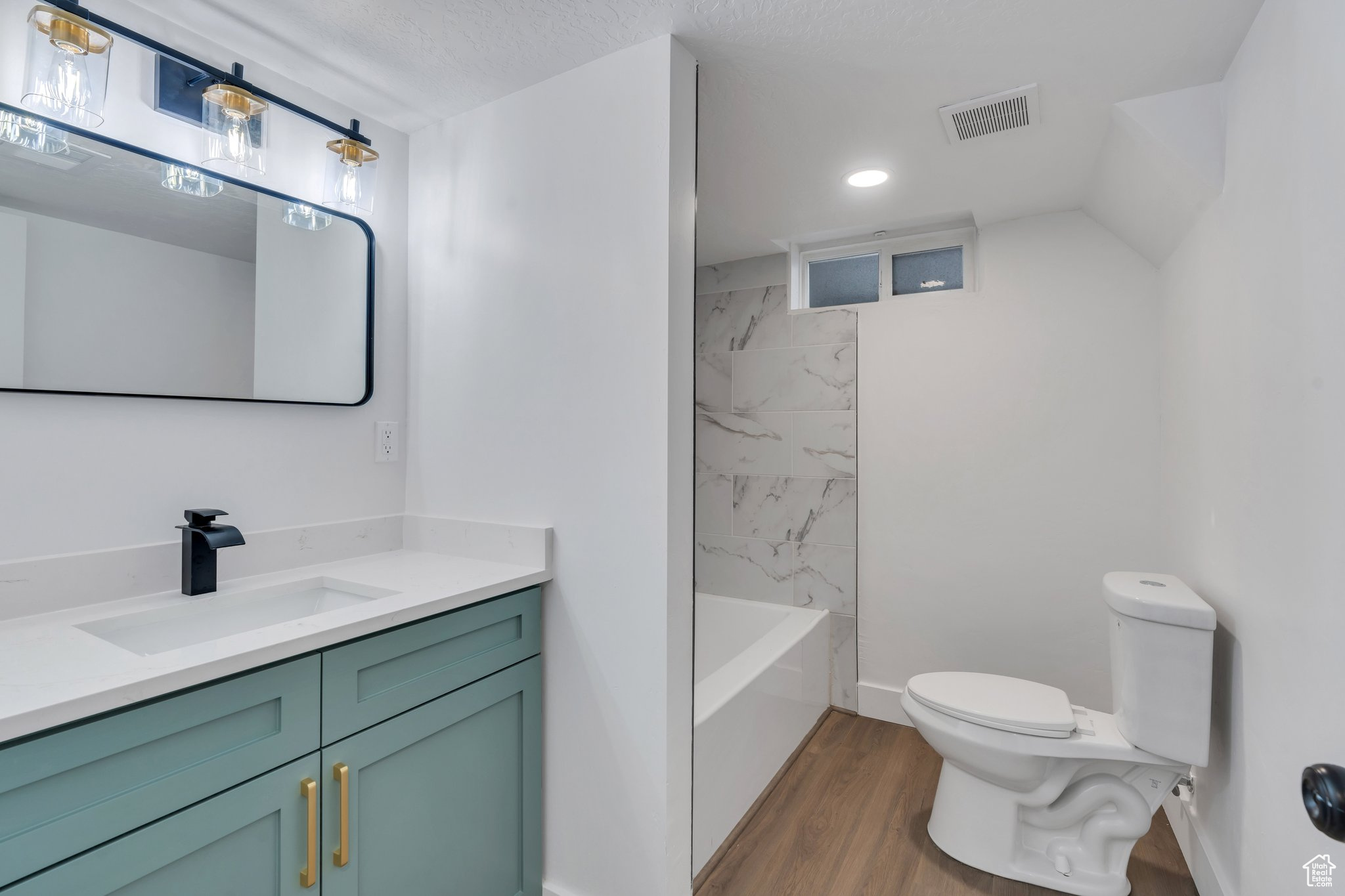 Full bathroom featuring a textured ceiling, toilet, hardwood / wood-style flooring, vanity, and tiled shower / bath