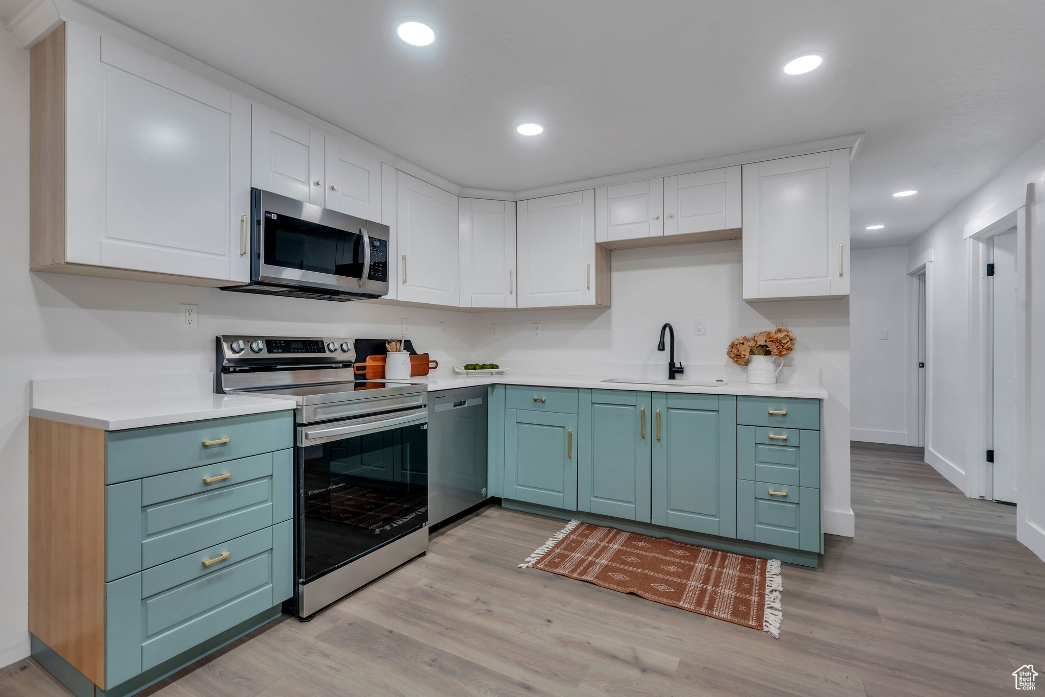 Kitchen with white cabinets, light hardwood / wood-style floors, sink, and stainless steel appliances