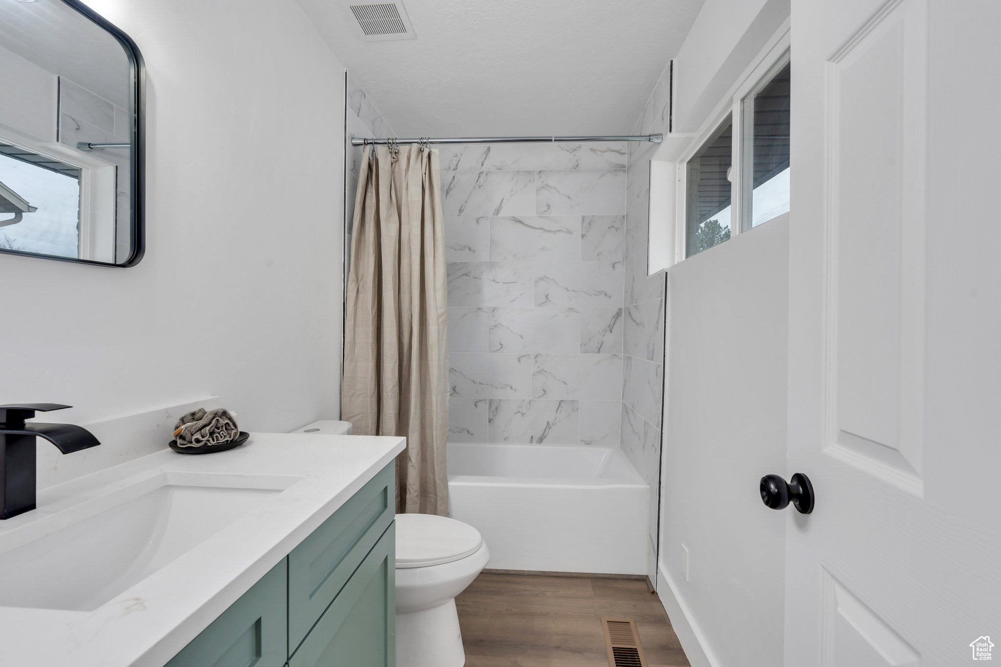 Full bathroom featuring hardwood / wood-style floors, vanity, toilet, and shower / bathtub combination with curtain