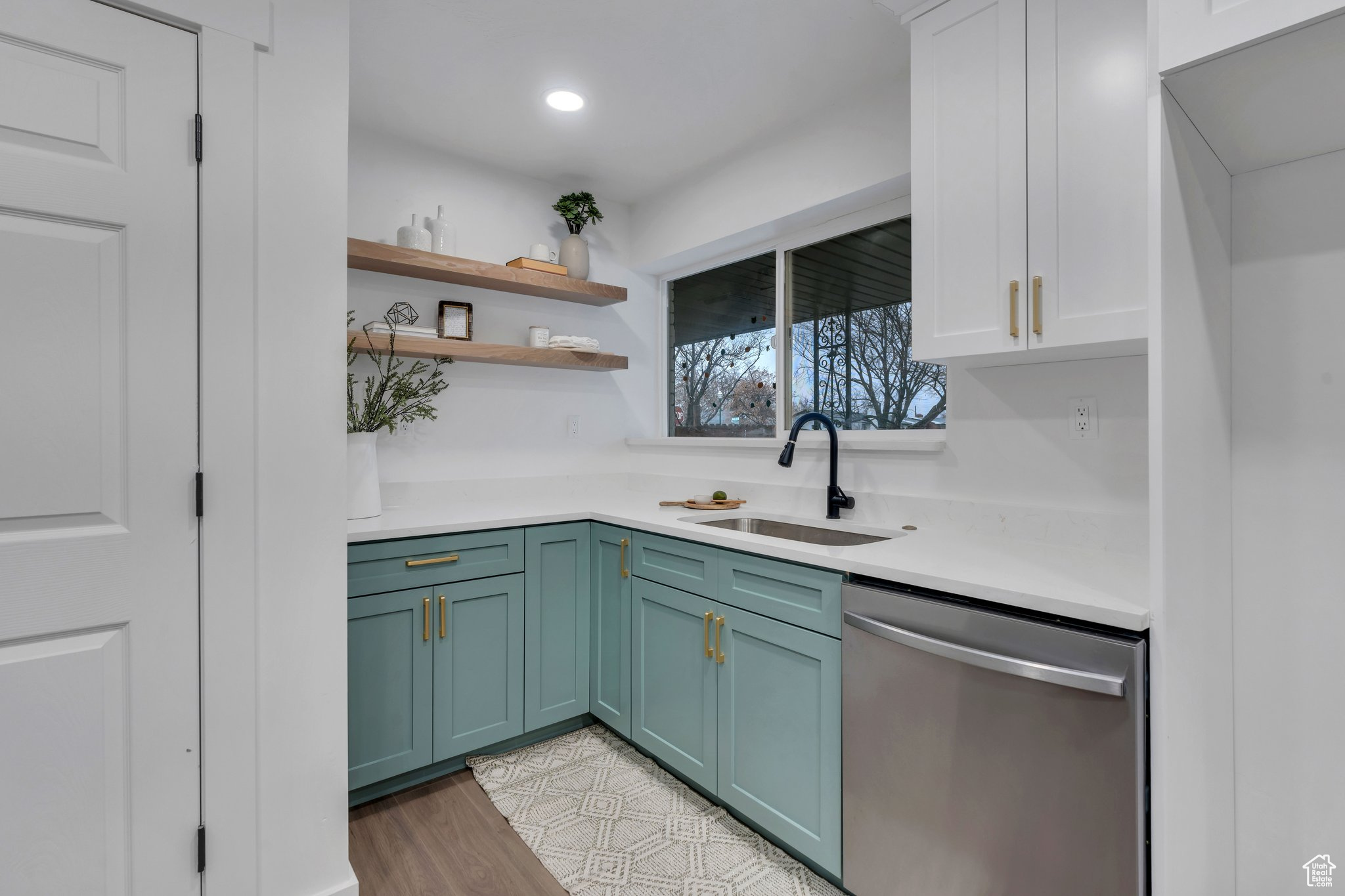 Kitchen with white cabinetry, dishwasher, light hardwood / wood-style flooring, and sink