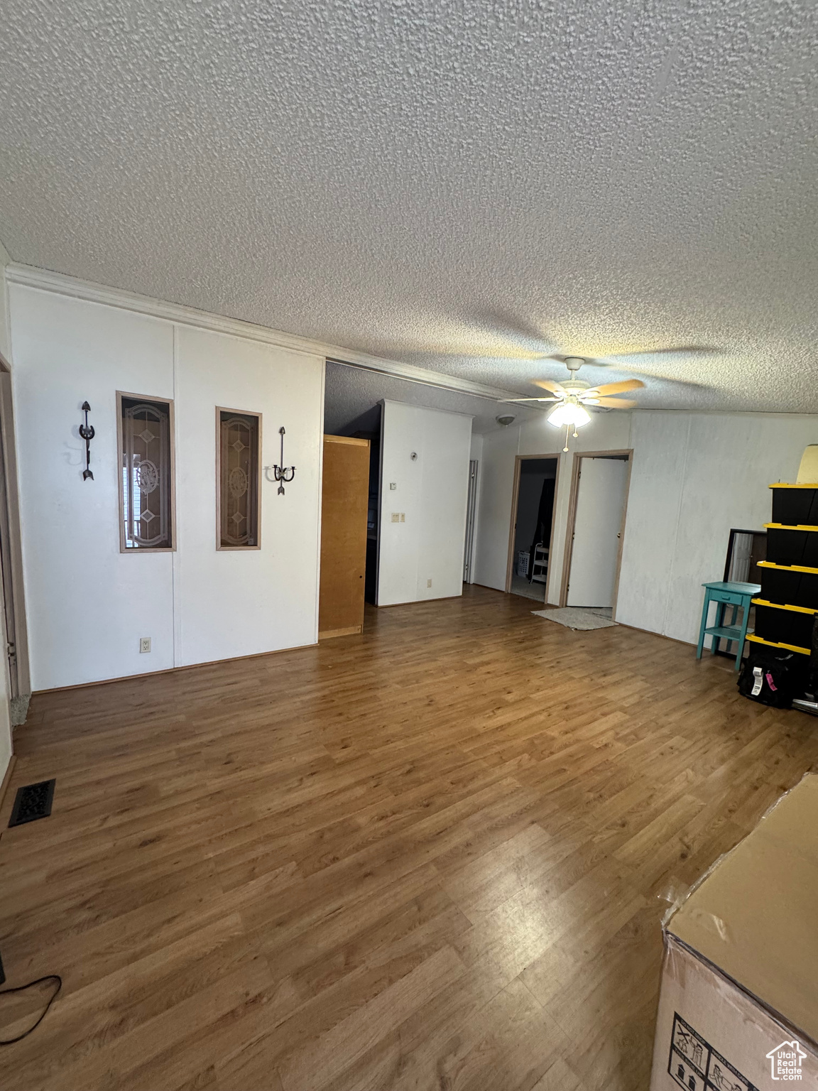 Unfurnished living room with a textured ceiling, hardwood / wood-style flooring, and ceiling fan