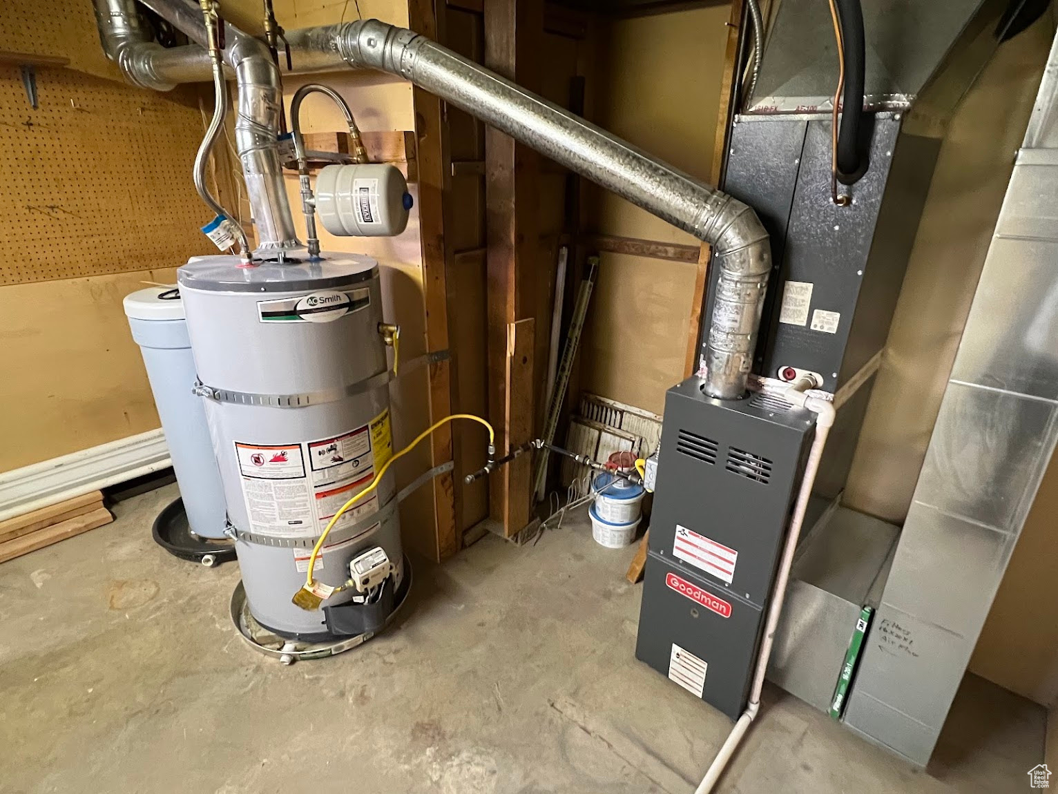 Utility room featuring strapped water heater and heating unit