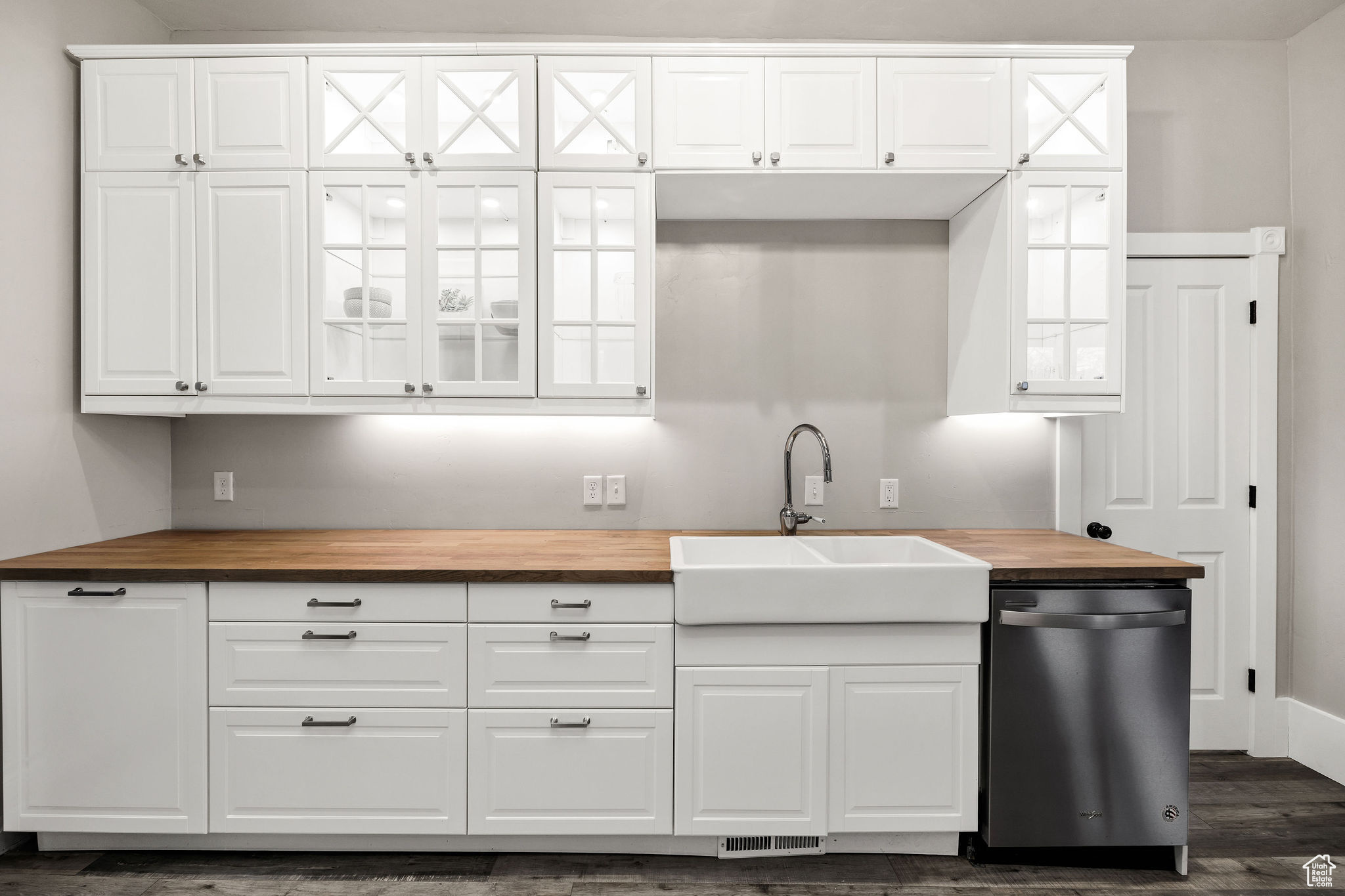 Kitchen with butcher block counters, white cabinetry, sink, and dishwasher