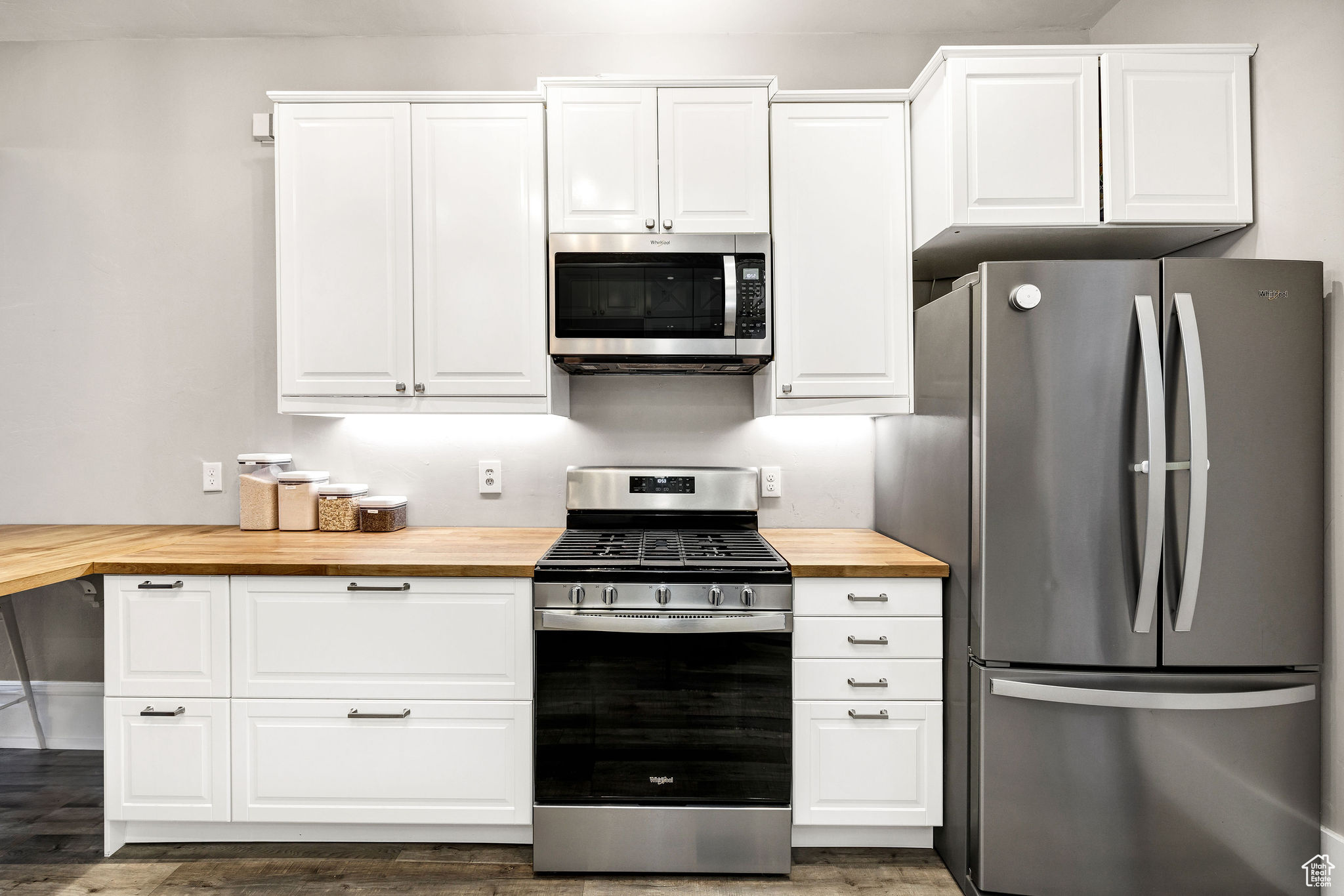 Kitchen featuring stainless steel appliances, white cabinetry, and butcher block counters