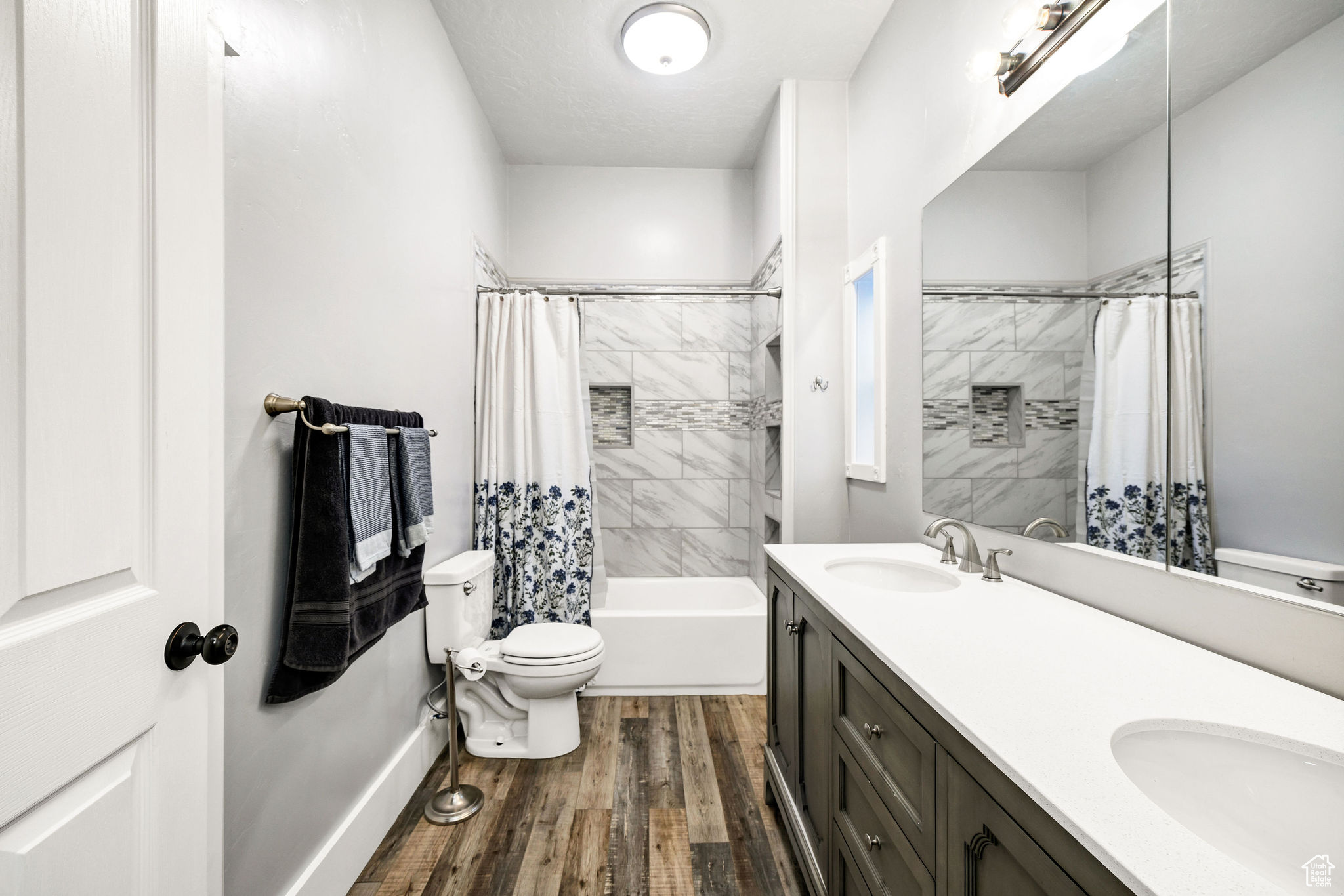 Full bathroom with shower / bath combination with curtain, vanity, wood-type flooring, and toilet