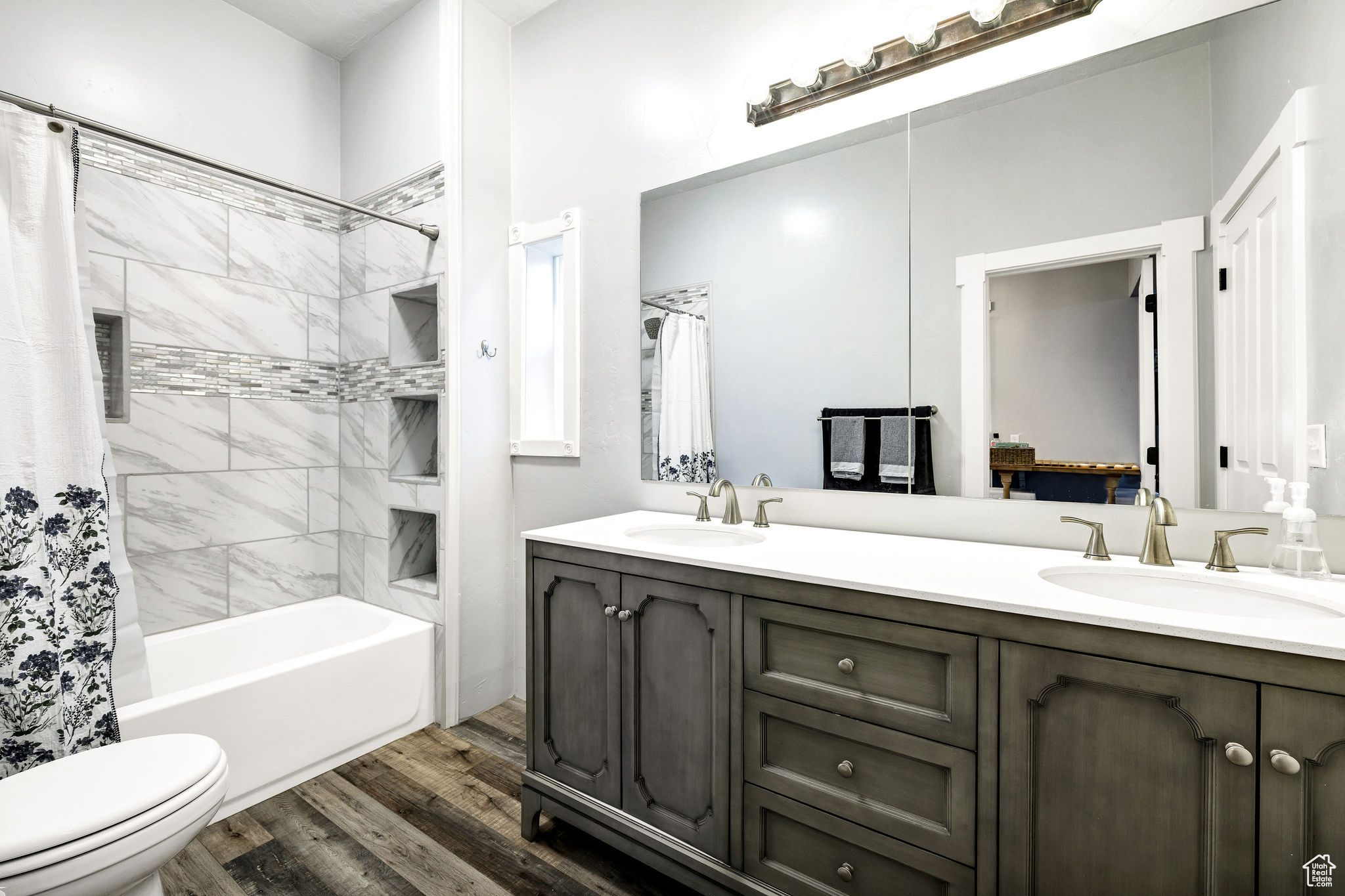 Full bathroom with hardwood / wood-style flooring, vanity, shower / bath combination with curtain, and toilet