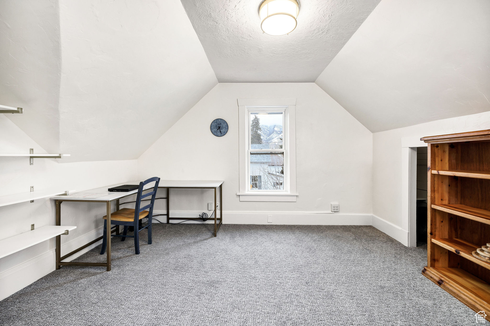 Carpeted bedroom featuring a textured ceiling and vaulted ceiling