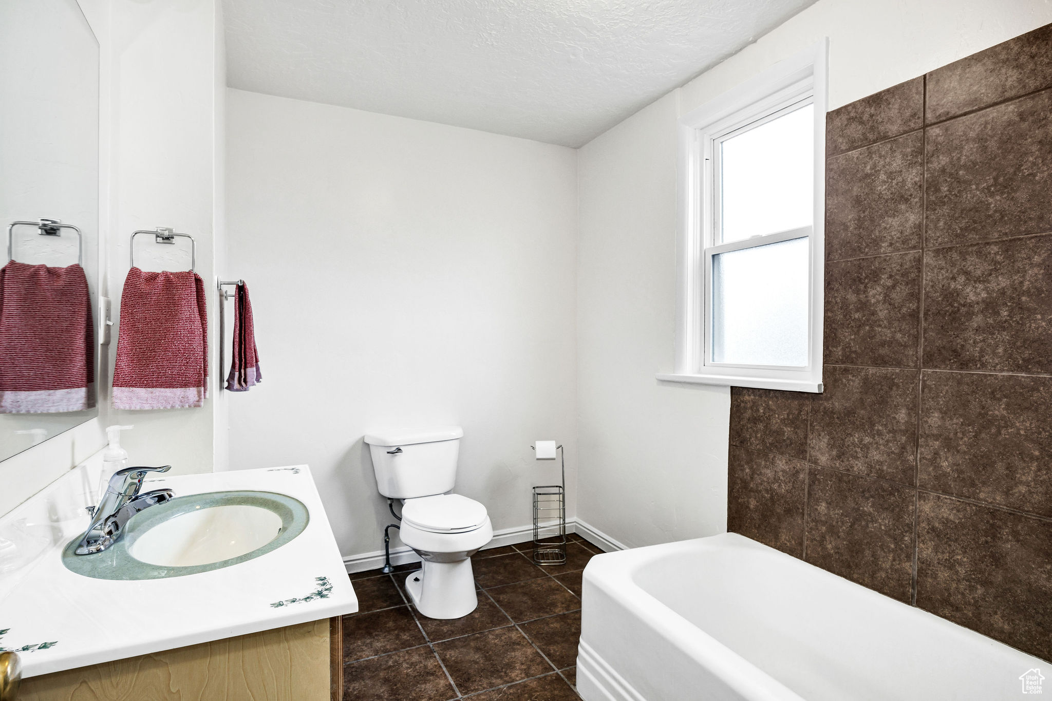 Bathroom with a washtub, tile patterned flooring, a textured ceiling, toilet, and vanity