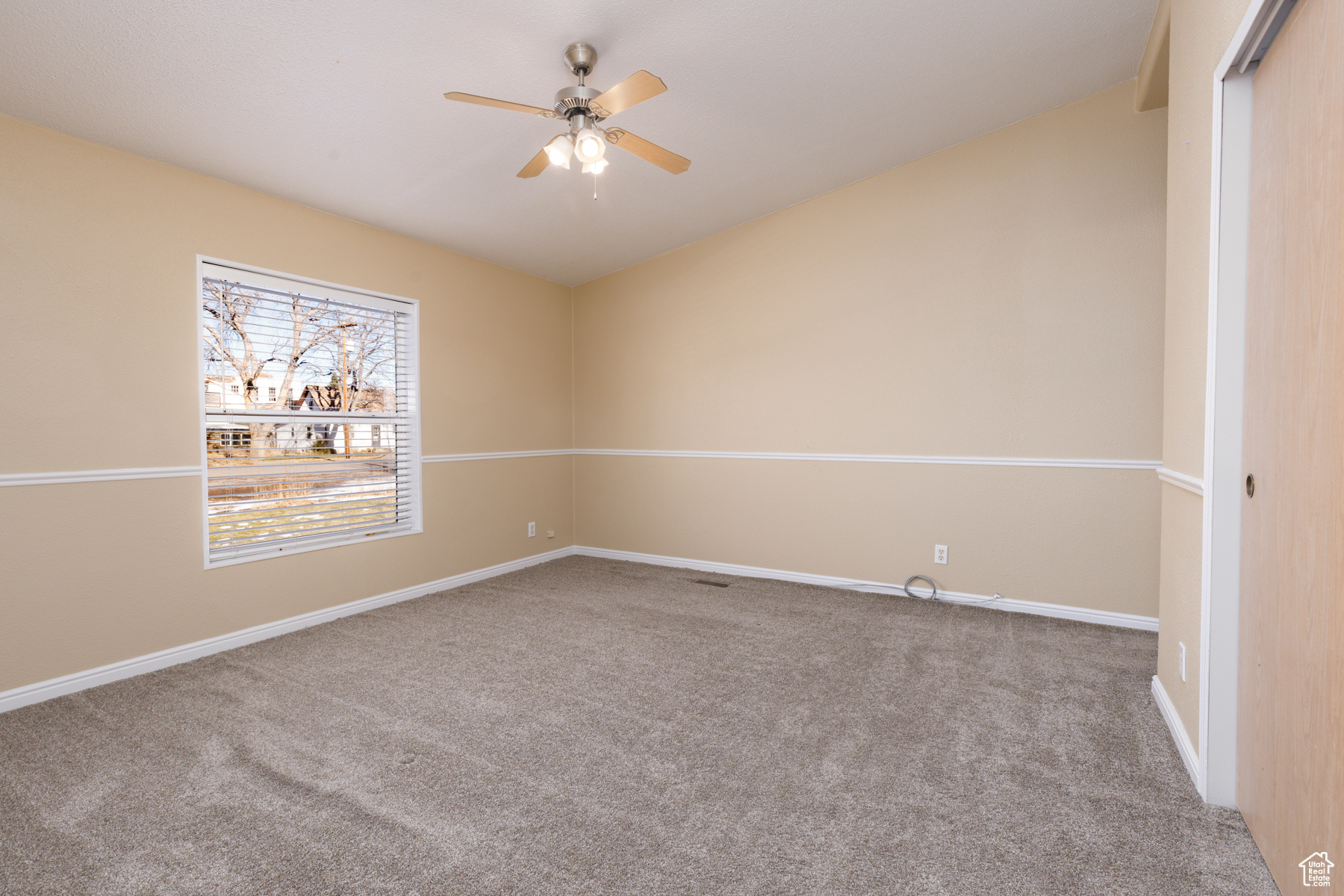 Carpeted spare room with ceiling fan