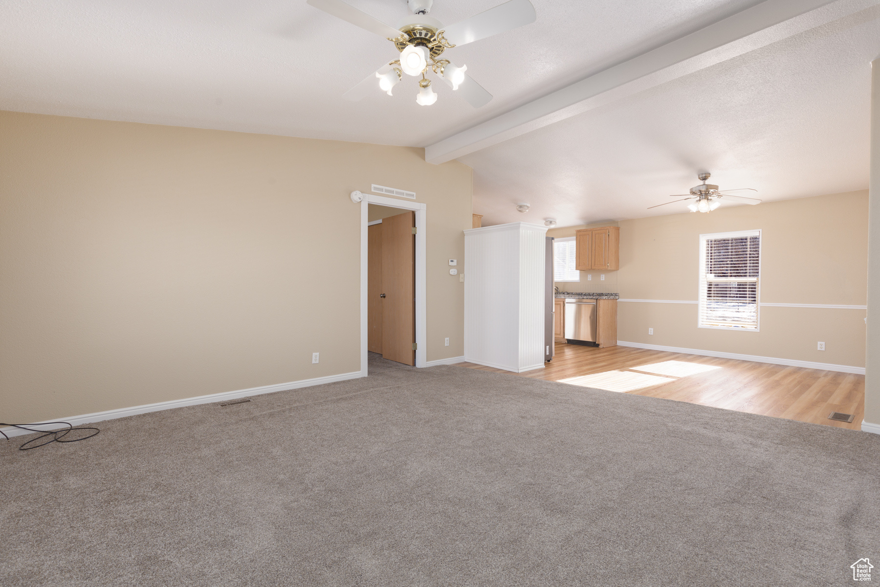 Unfurnished living room with ceiling fan, lofted ceiling with beams, and light carpet