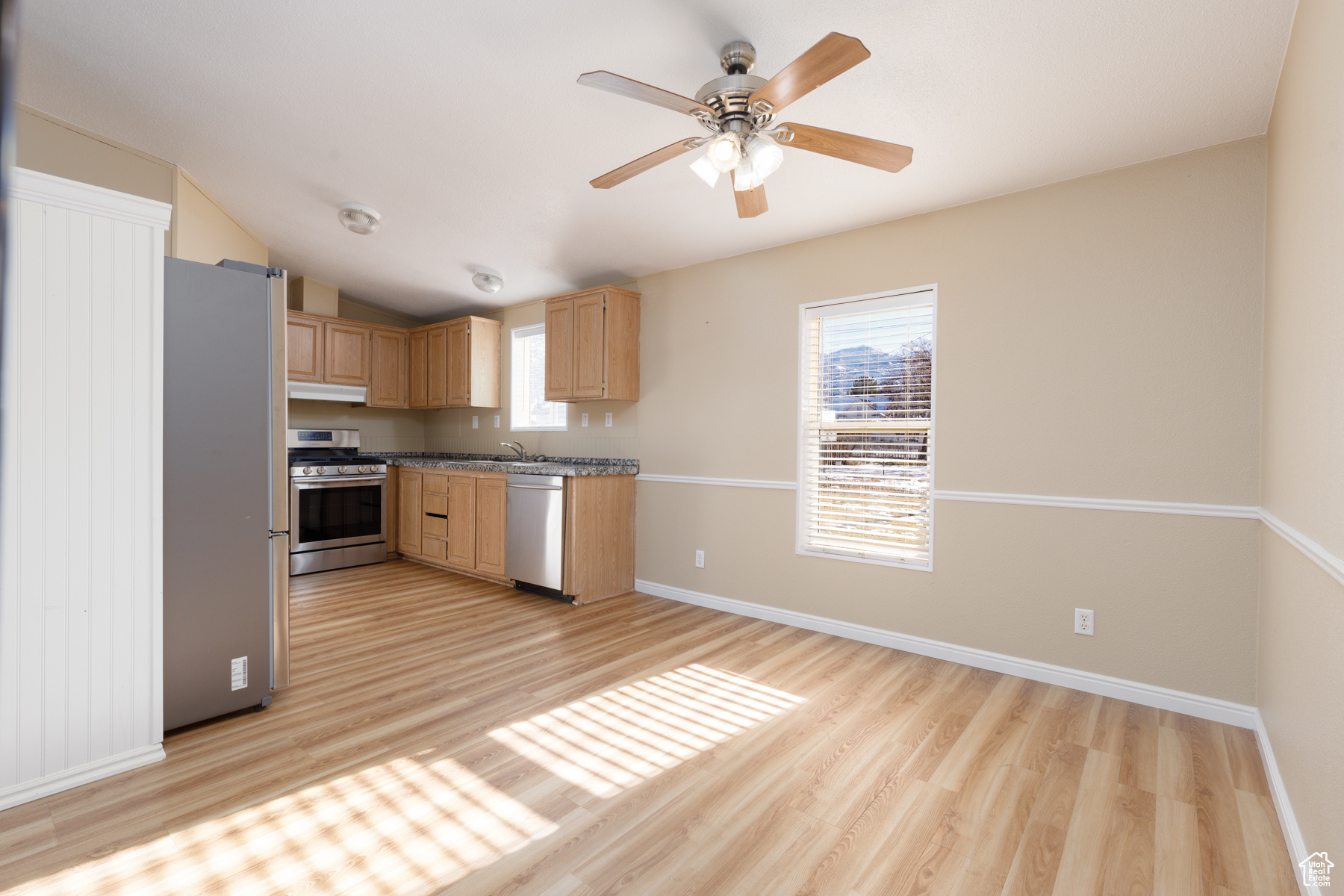 Kitchen with ceiling fan, lofted ceiling, light brown cabinetry, appliances with stainless steel finishes, and light wood-type flooring