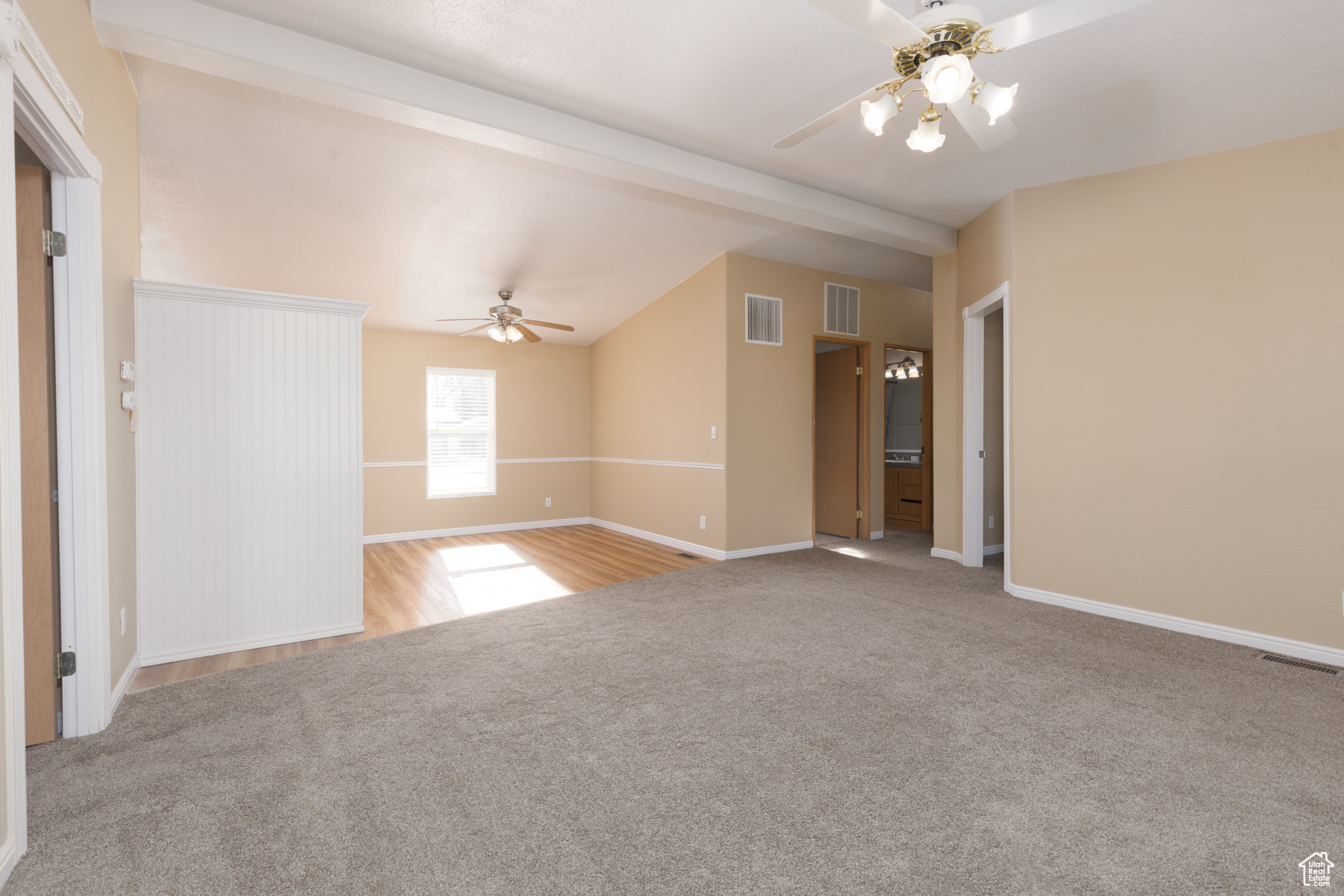 Carpeted empty room with lofted ceiling with beams and ceiling fan