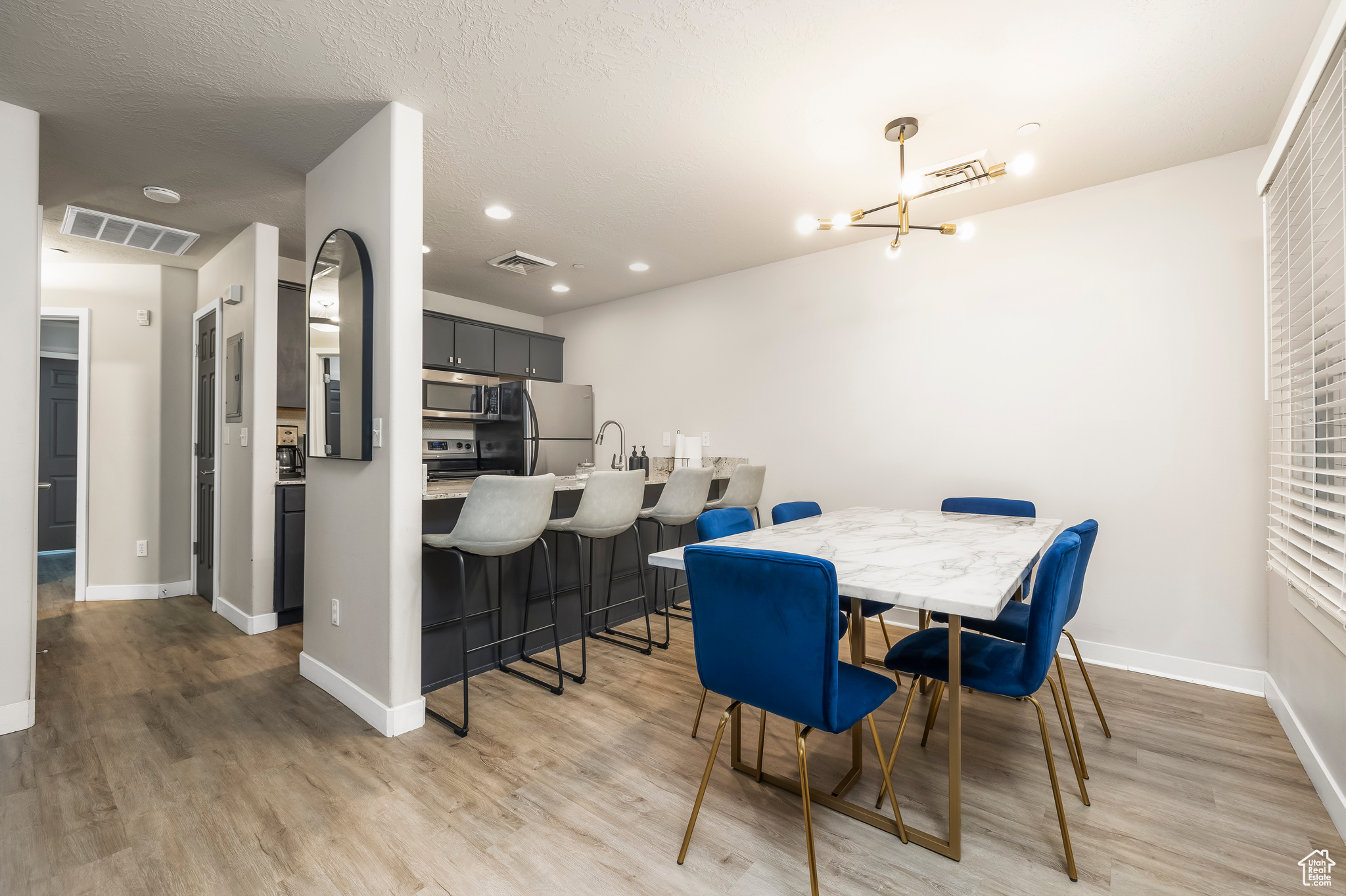 Dining space with light hardwood / wood-style flooring, a textured ceiling, and an inviting chandelier