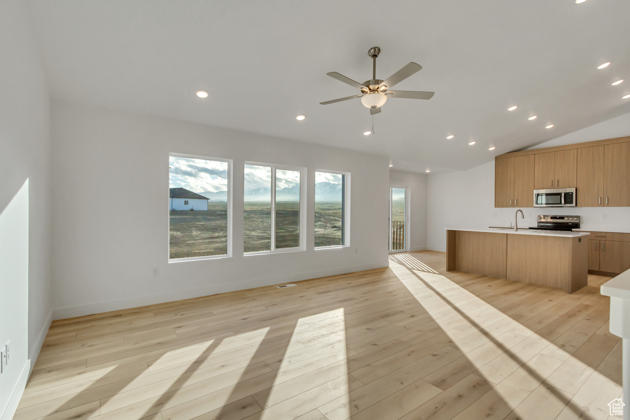 Kitchen featuring sink, vaulted ceiling, light hardwood / wood-style flooring, ceiling fan, and stainless steel appliances